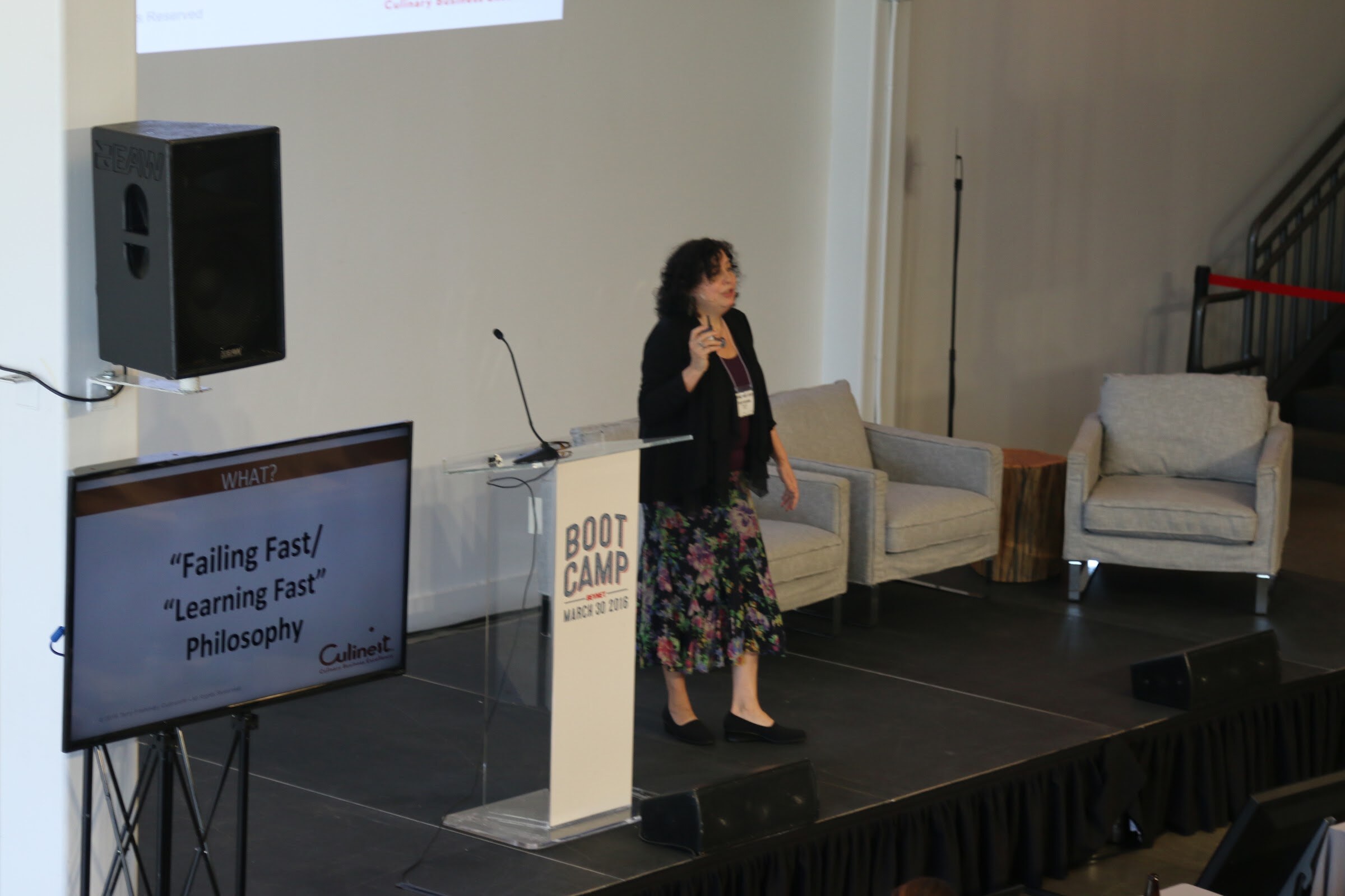 Presenter at podium, monitor shows Failing Fast / Learning Fast Philosophy (Culinet).
