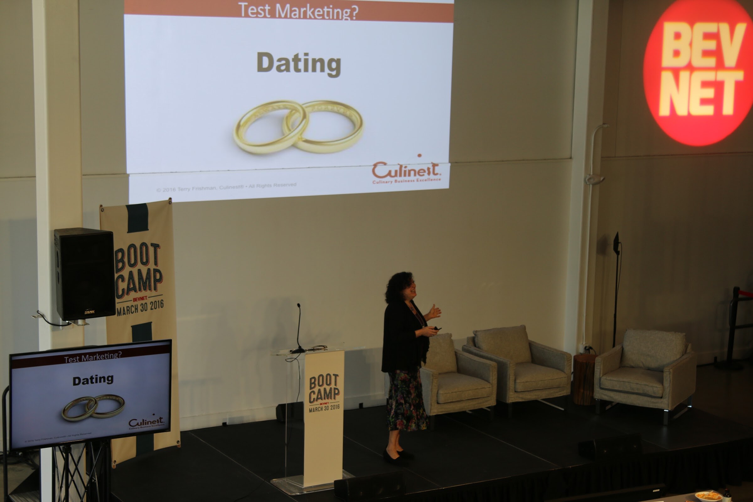 Presenter on stage elevated view, slide Test Marketing? Dating with two gold rings (Culinet logo), BevNET logo wall.