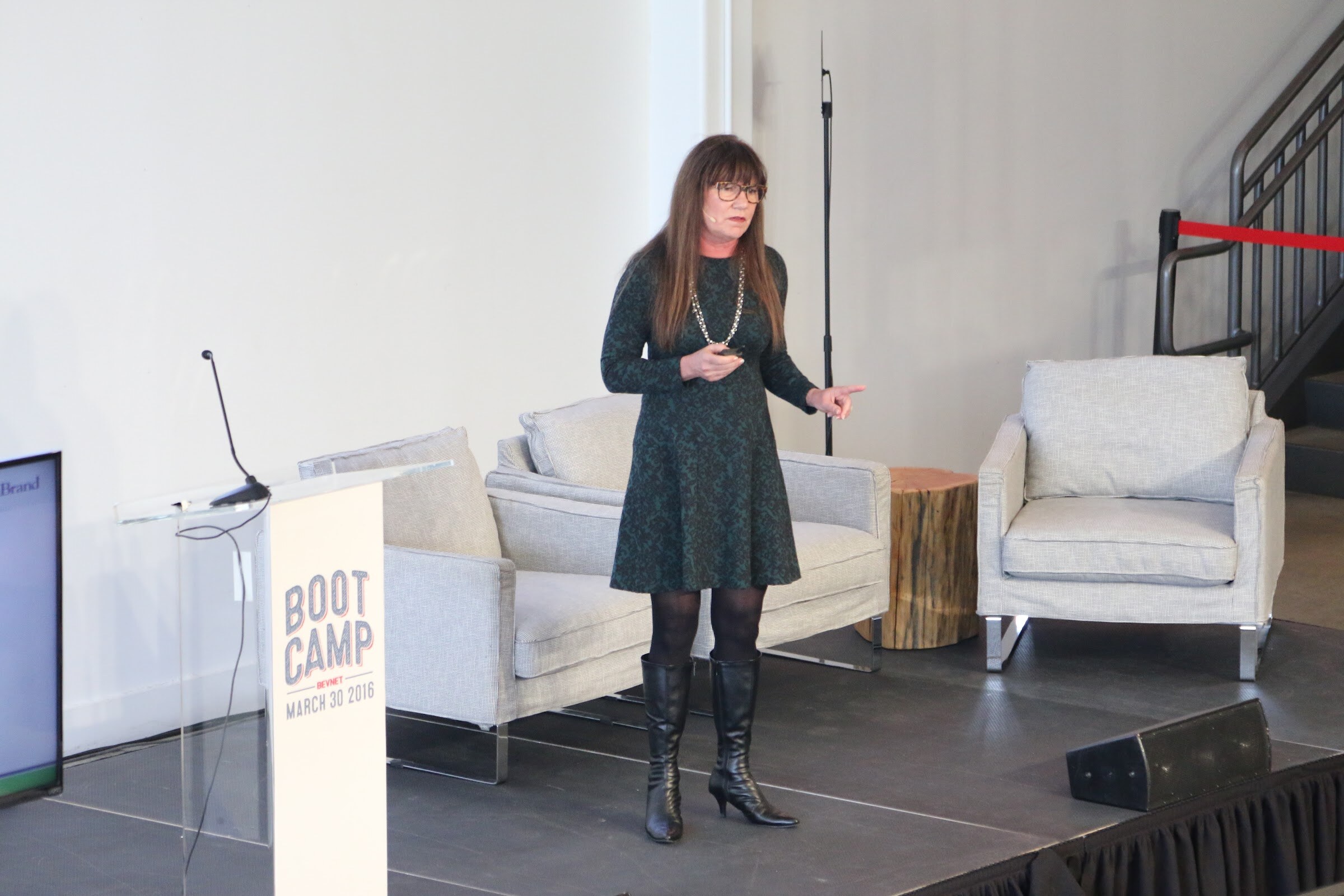 Presenter pointing, stage with podium and armchairs.