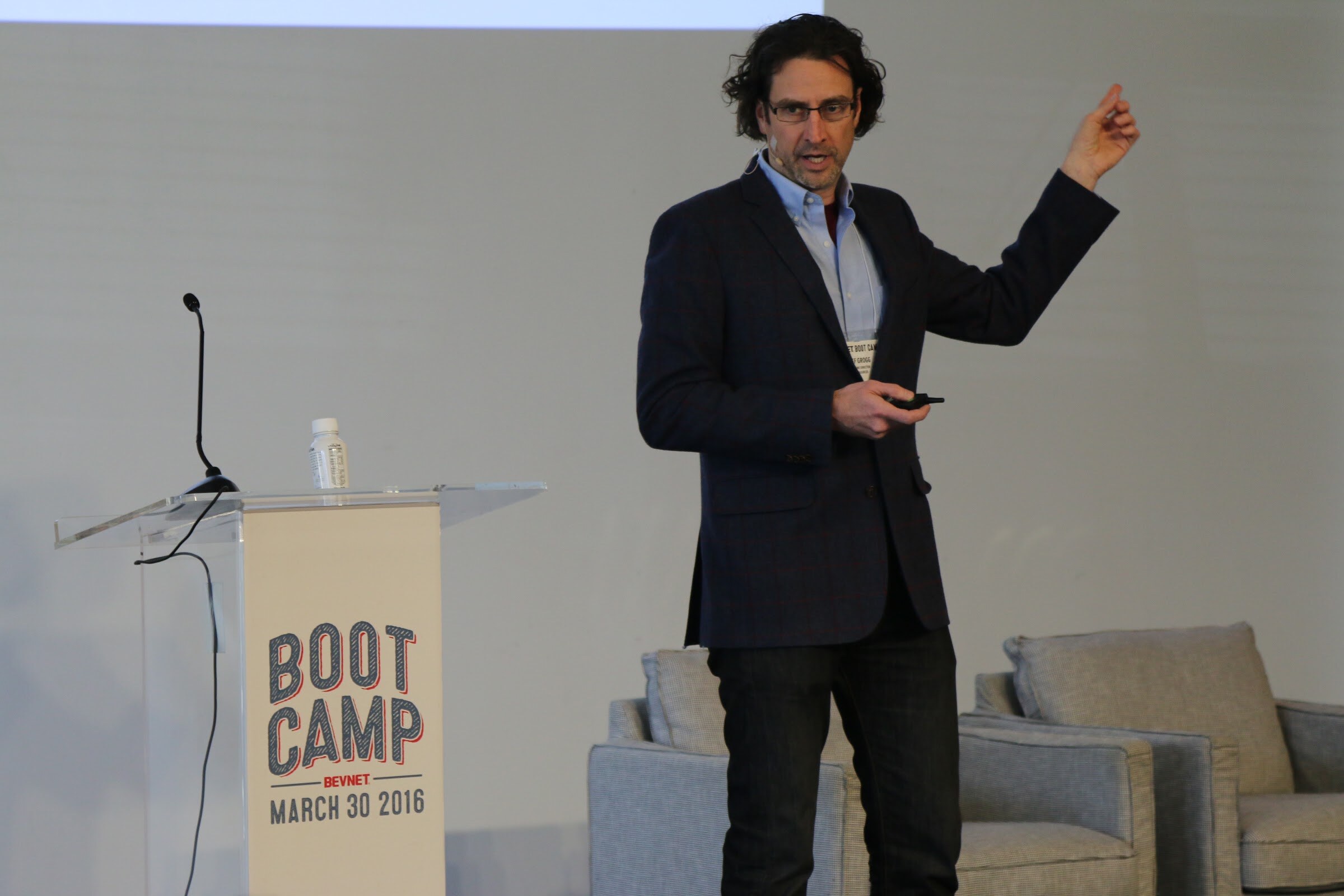 Presenter pointing upward beside Boot Camp podium.