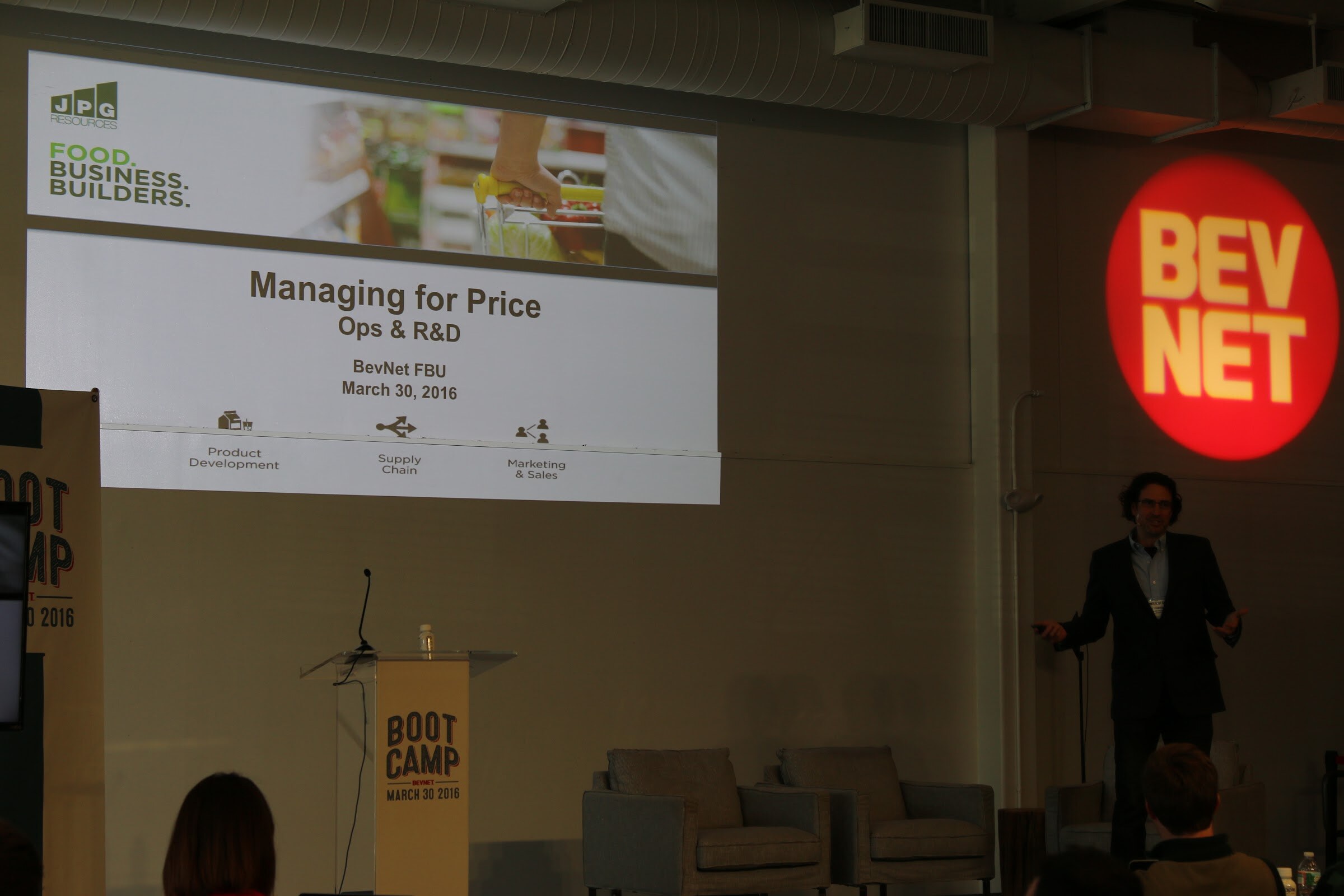 Presenter right of stage, slide Managing for Price Ops and R&D, BevNET projected logo.