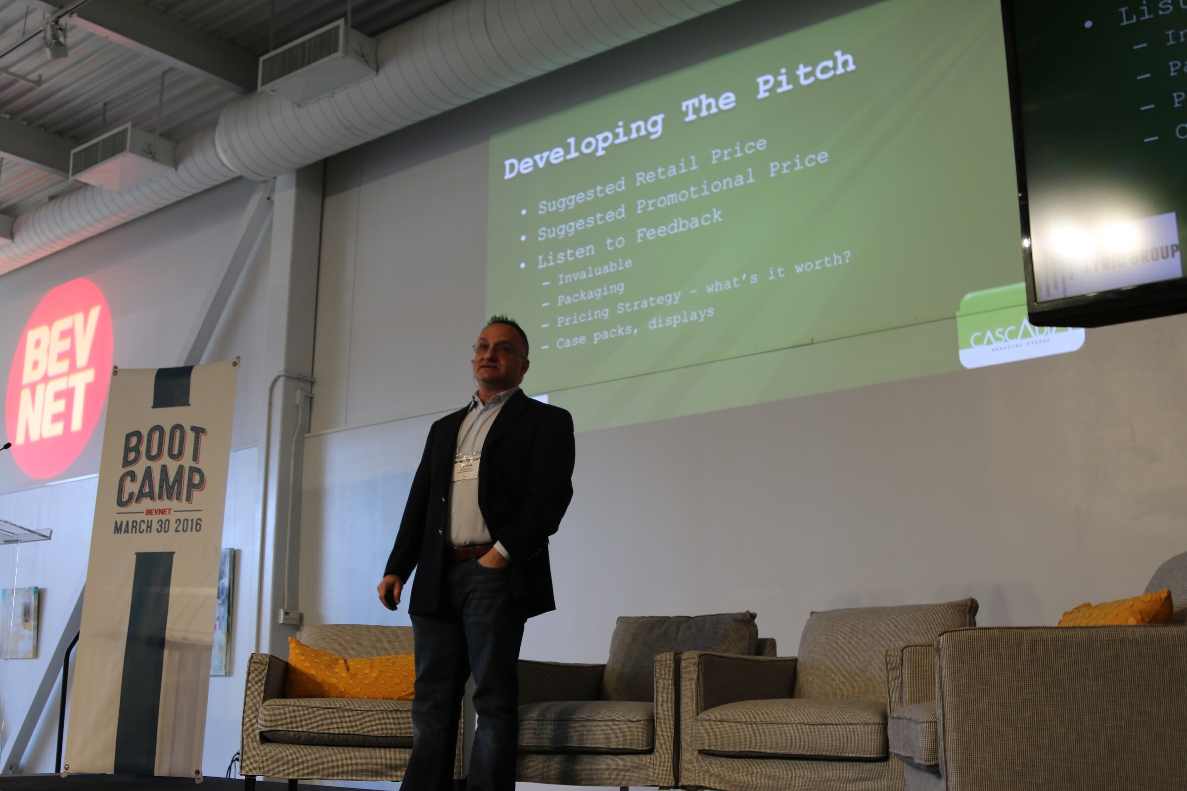 Presenter stands before slide Developing The Pitch suggested retail price, BevNET logo wall.