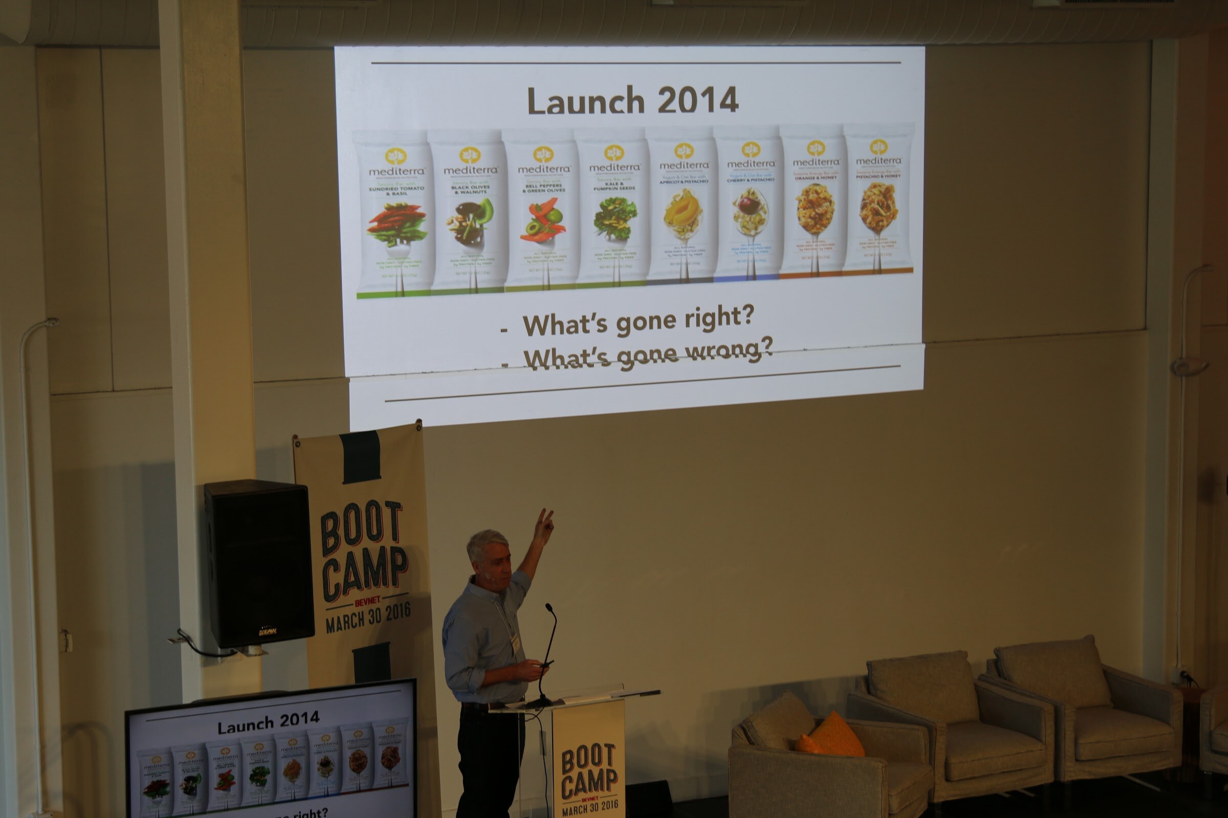 Speaker points to slide Launch 2014 with row of Mediterra pouches, What's gone right/wrong.