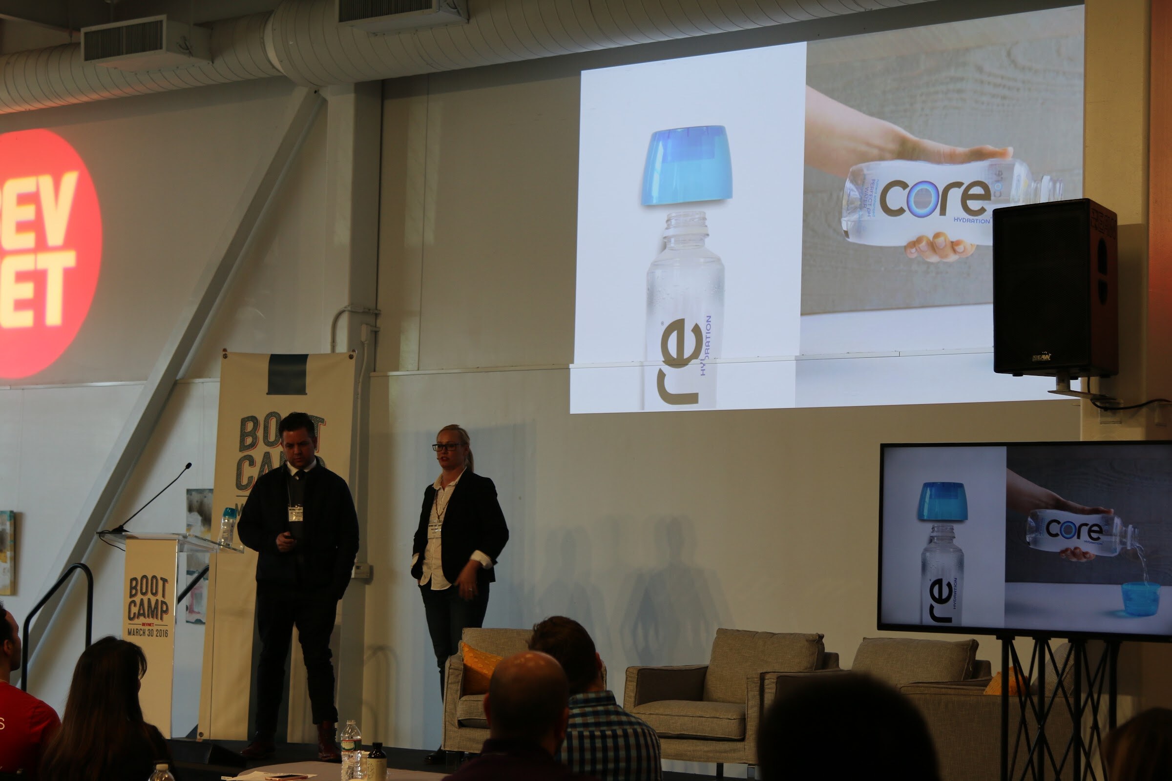Two presenters, Core Hydration slide with bottle, BevNET logo on wall.