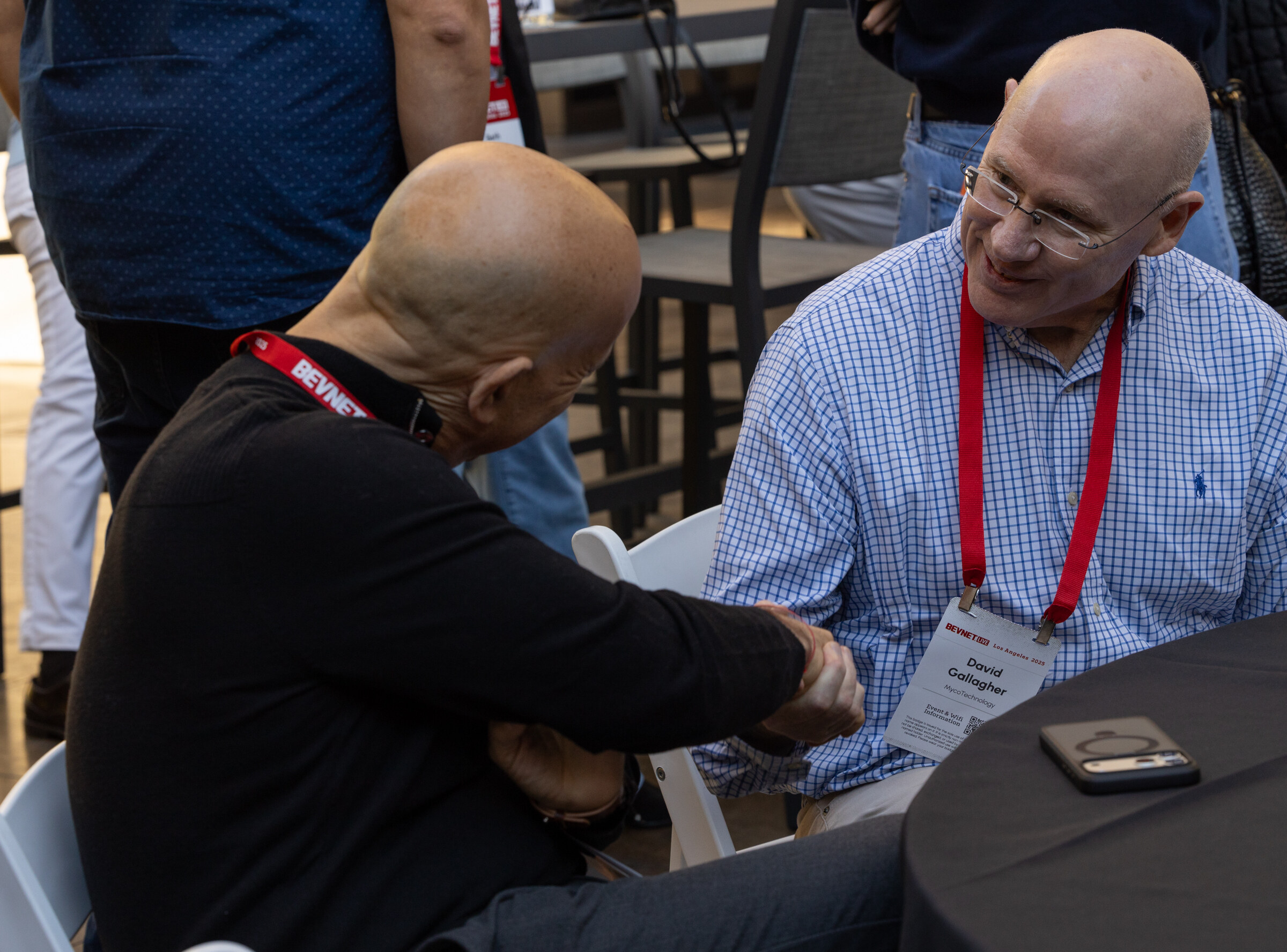 Two men shake hands at a table during the Boot Camp round tables.