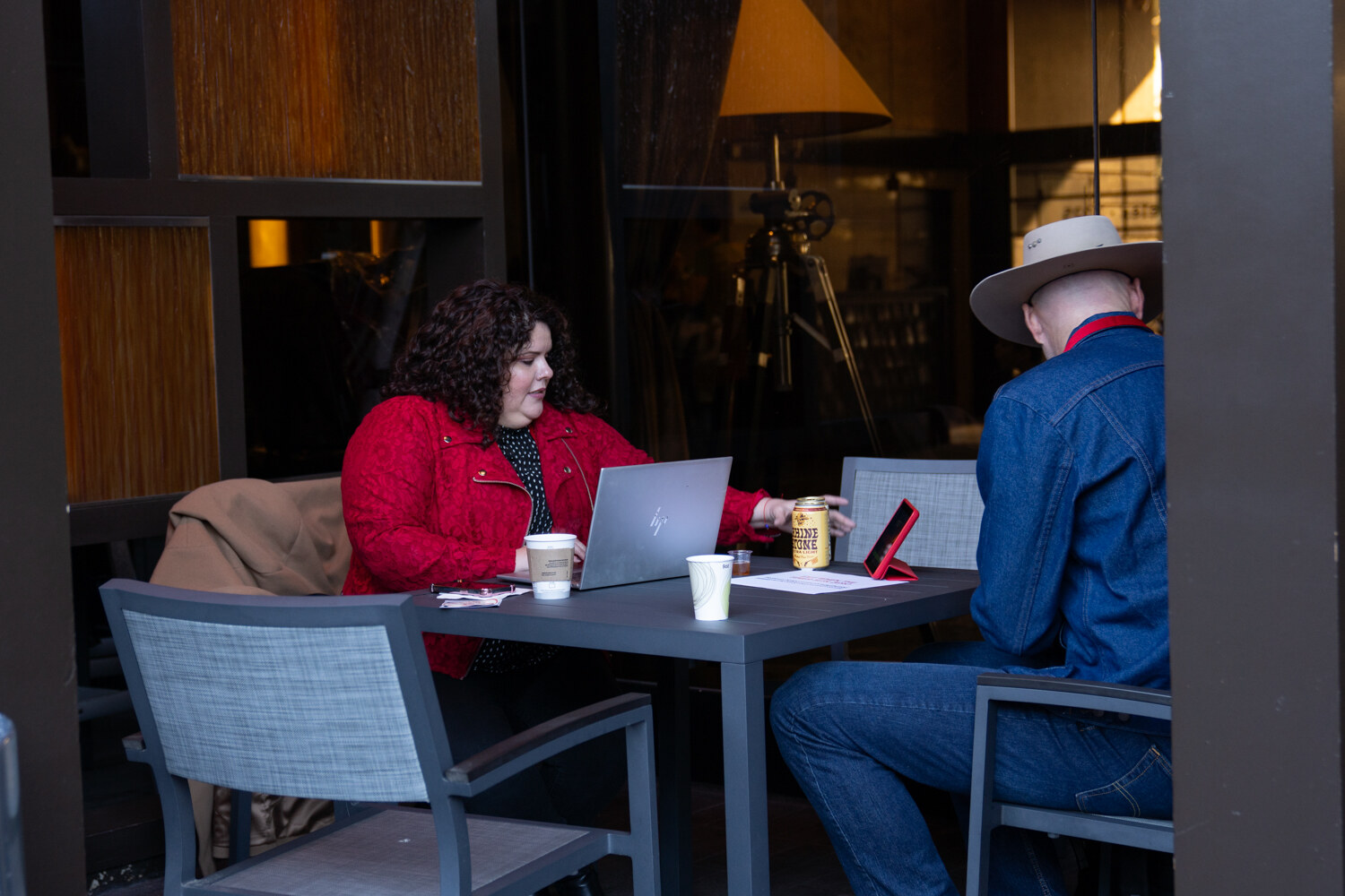 Two men talk at a patio table.