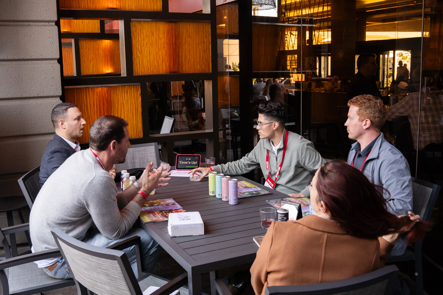 A group sits around a table covered in cans and notes.