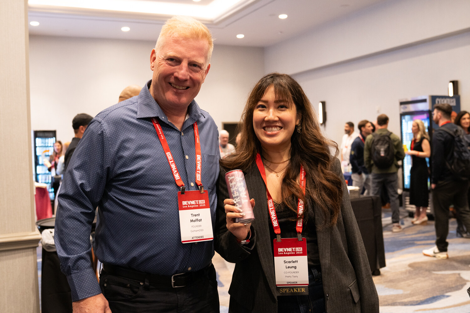A man and woman wearing badges pose, the woman holding a can.