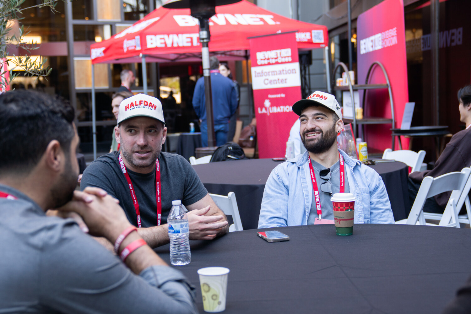 Two men in caps sit at a round table in the courtyard.