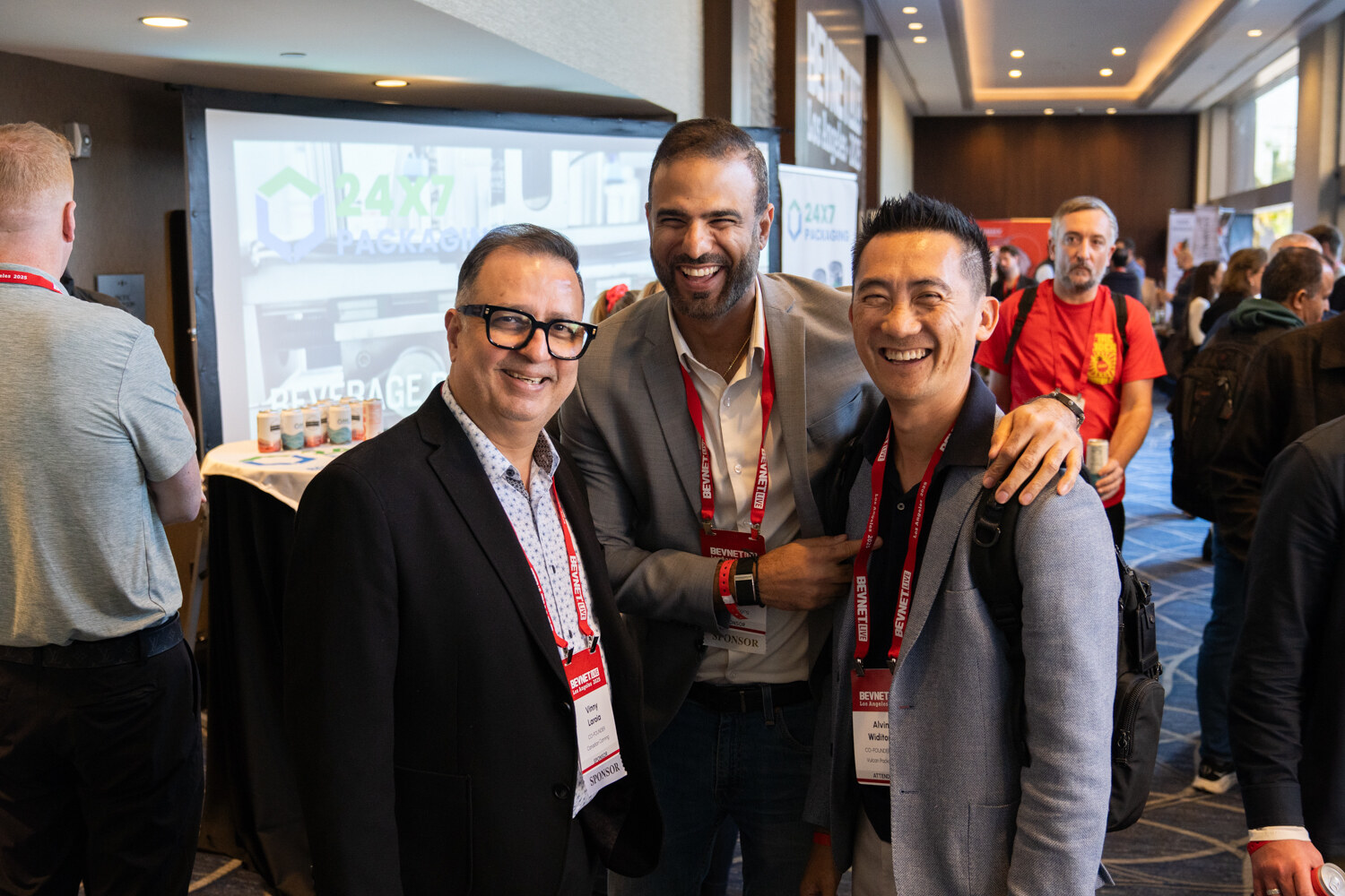 Three men in lanyards pose with arms around each other.