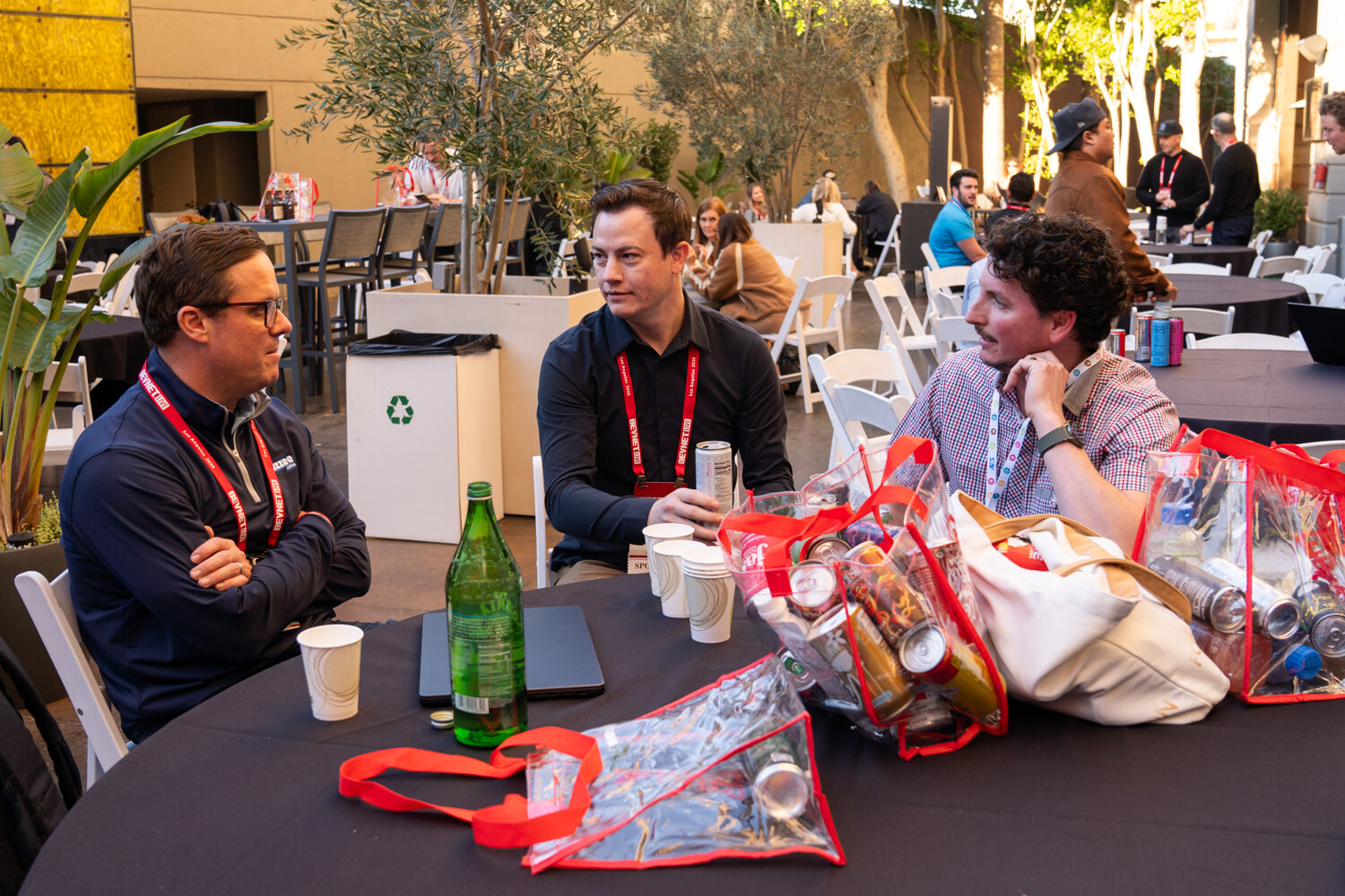 Attendees sit at a round table with red BevNET Live tote bags.