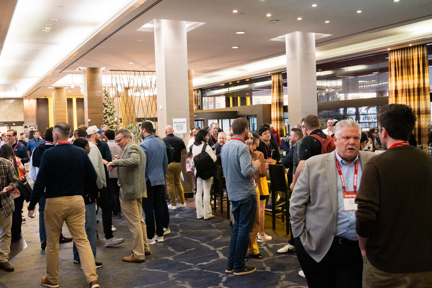 A crowd of attendees talks in a carpeted foyer.
