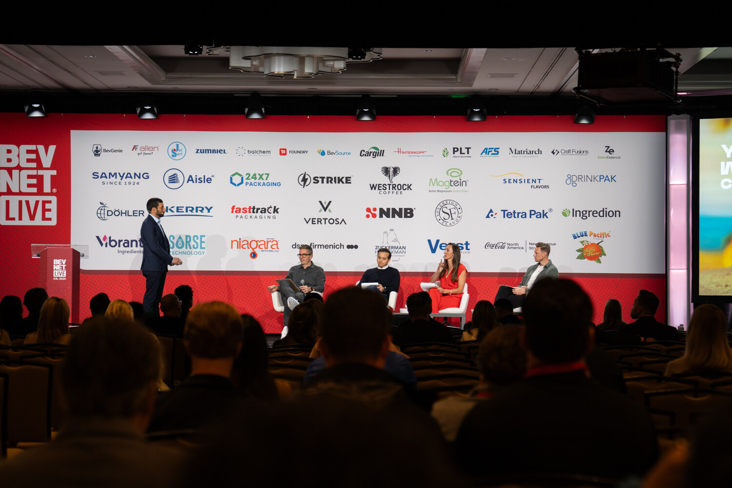 A wide shot of the stage with speakers and judges and a packed audience.