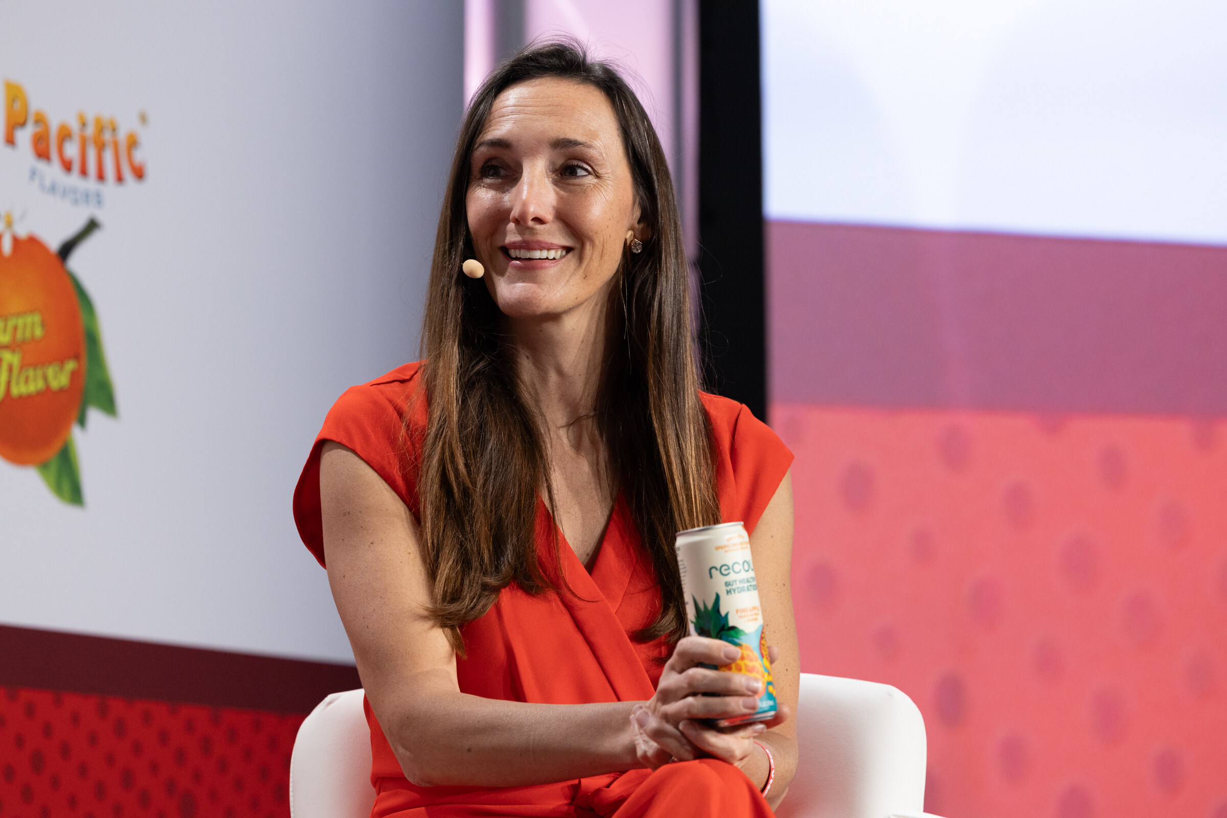 A woman in a red dress smiles while holding a can.