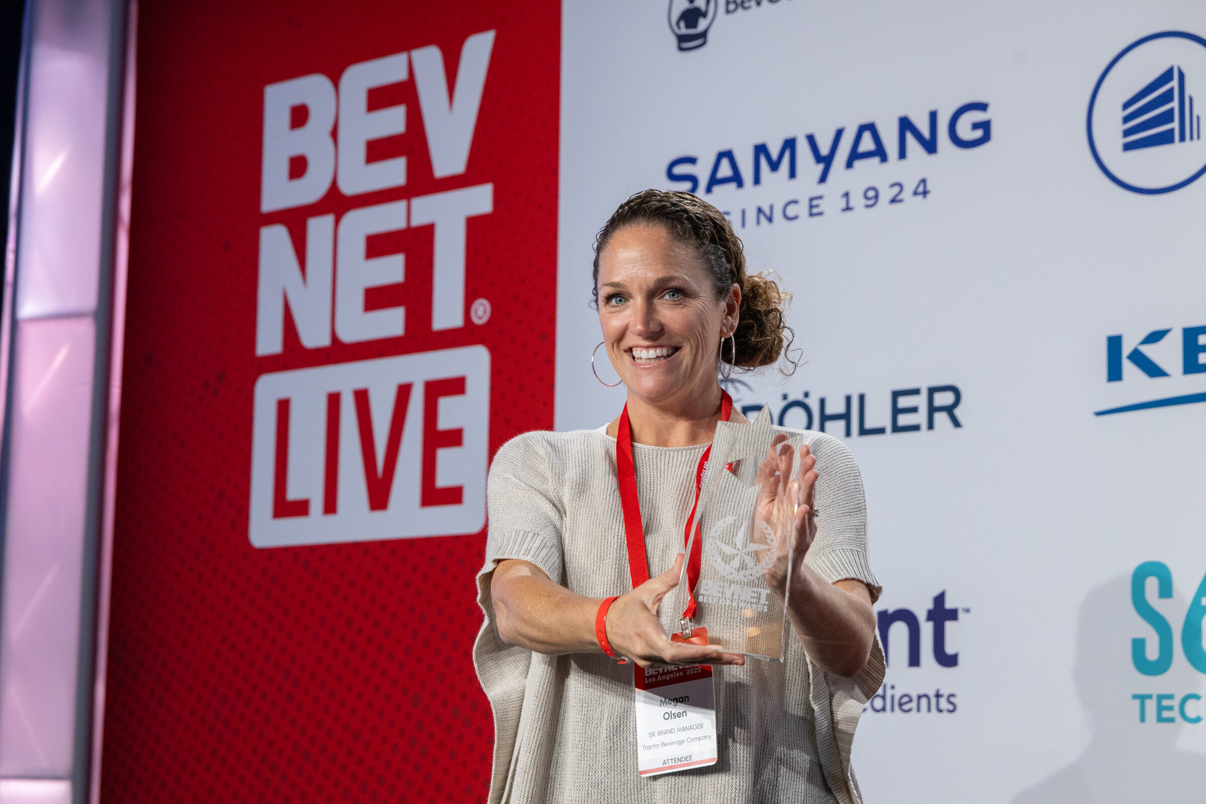 A smiling woman holds up a glass award on stage.
