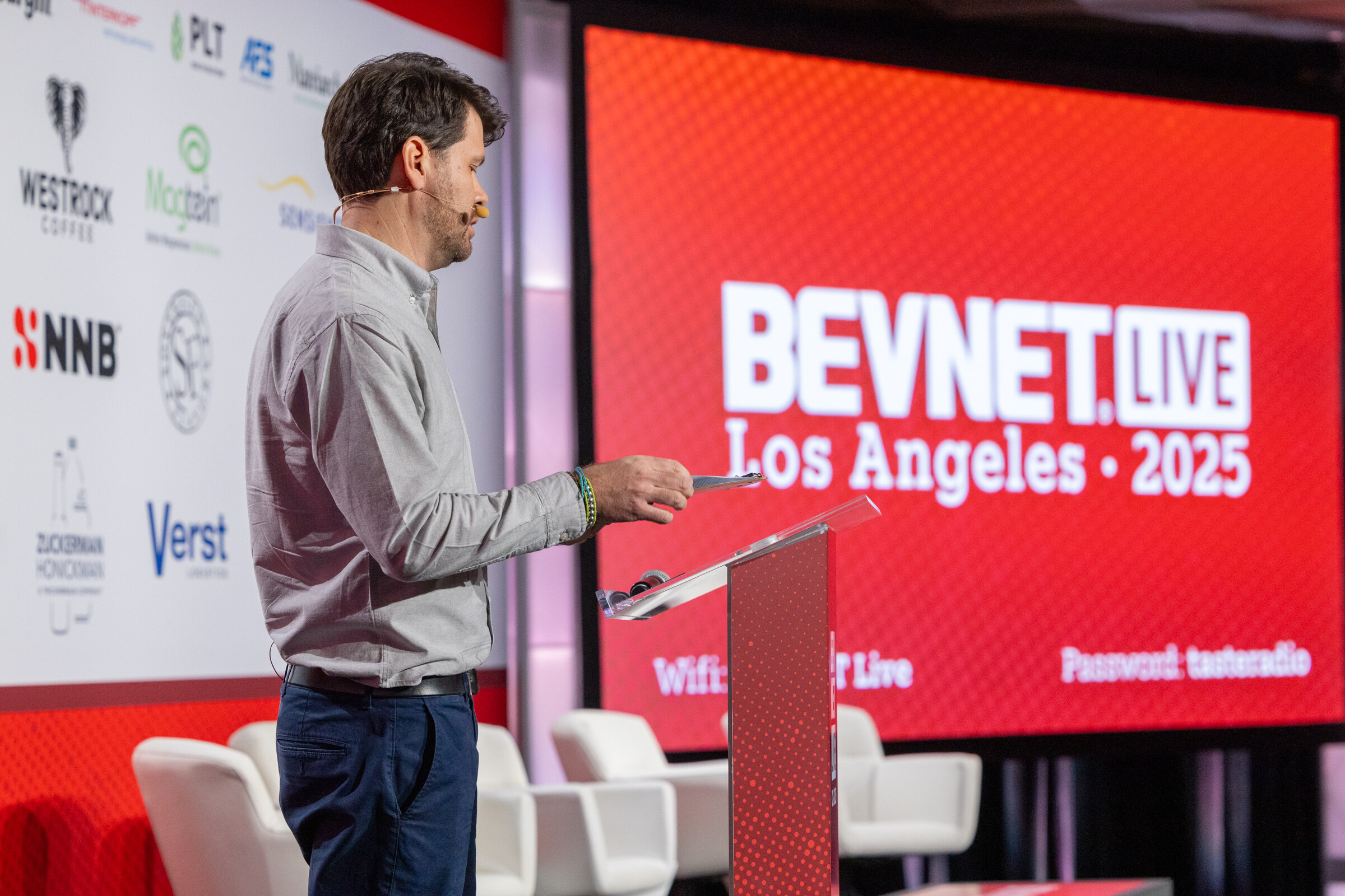 A man in a gray shirt speaks at a podium beside a BevNET Live Los Angeles 2025 slide.