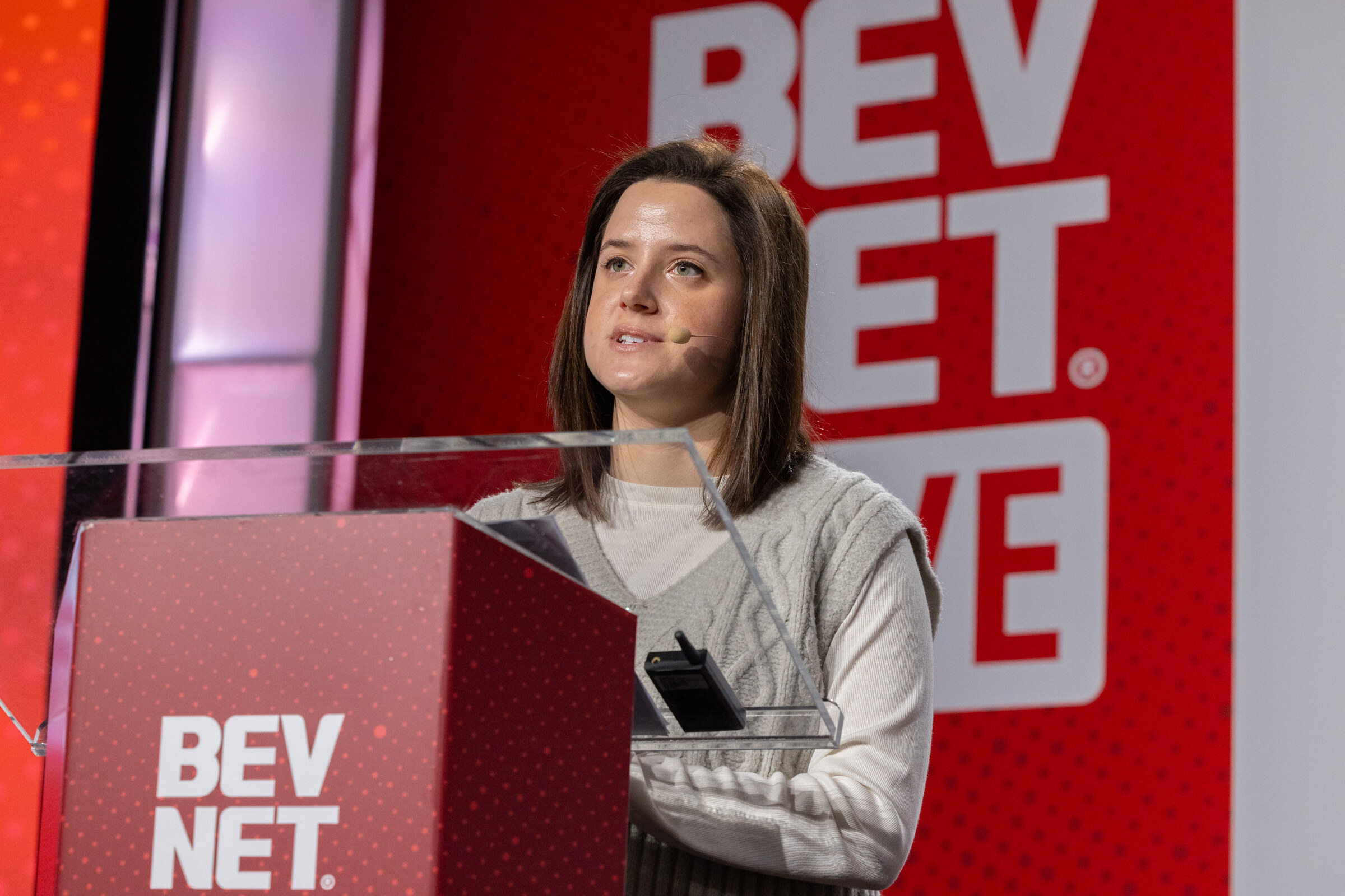 A woman stands at a BevNET podium and looks out at the audience.