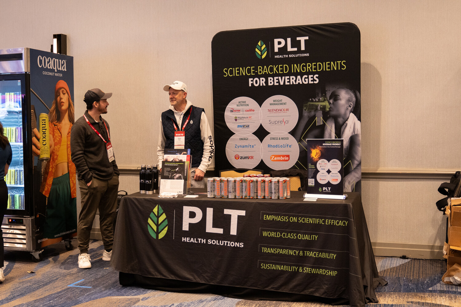 A booth with a black PLT Health Solutions banner and table.