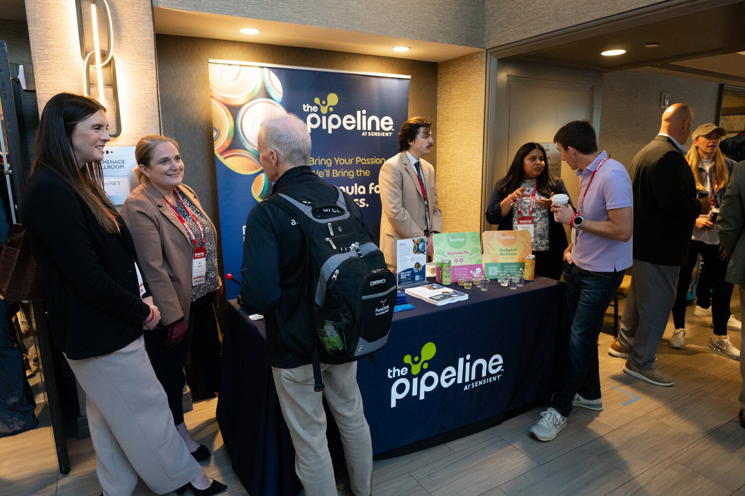 Attendees chat in front of a navy Pipeline banner and table.
