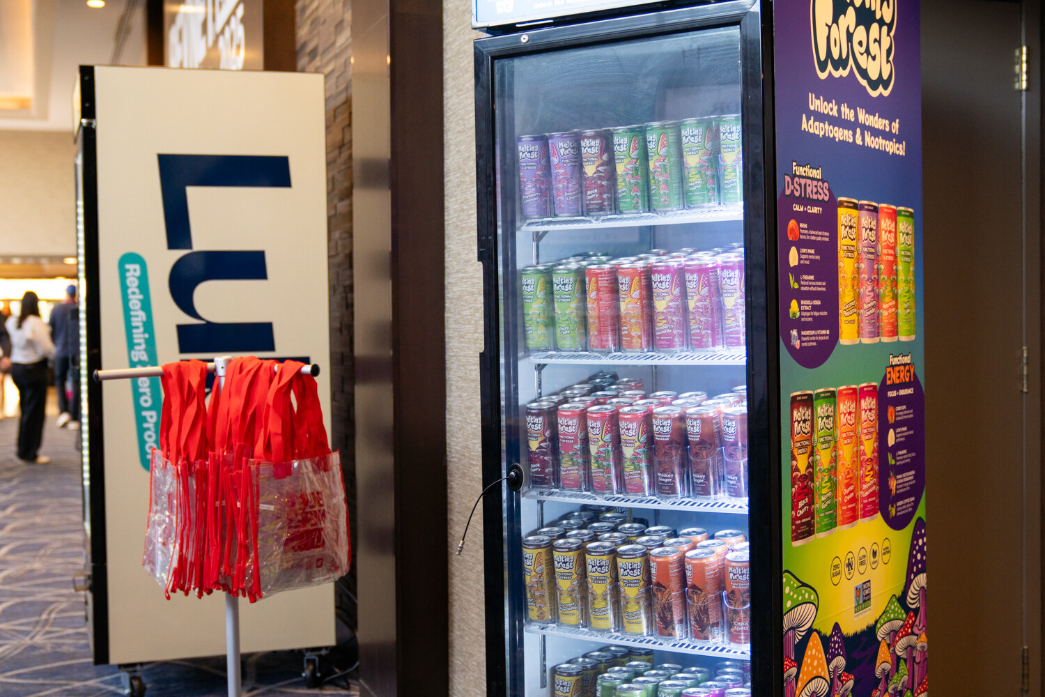 A fridge branded Luba stands beside red BevNET Live tote bags.