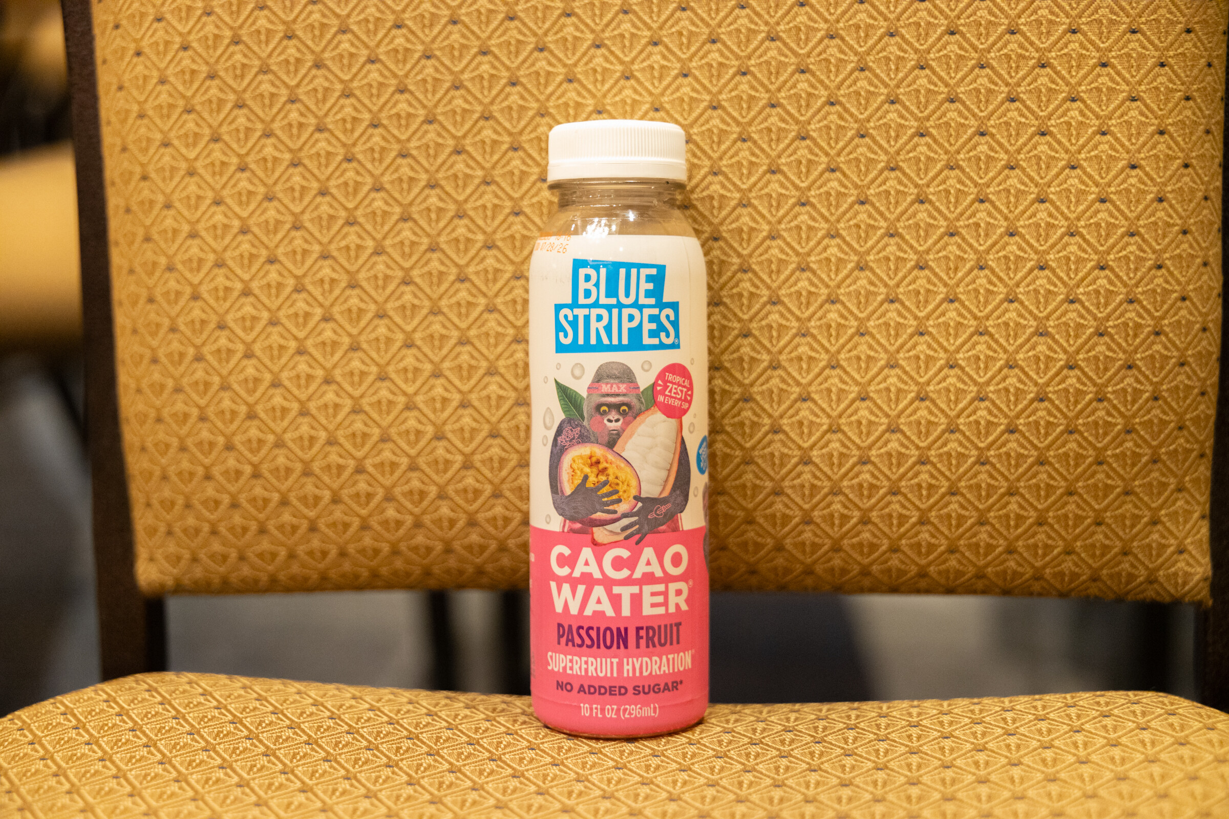 A Blue Stripes Cacao Water bottle stands on a gold ballroom chair.