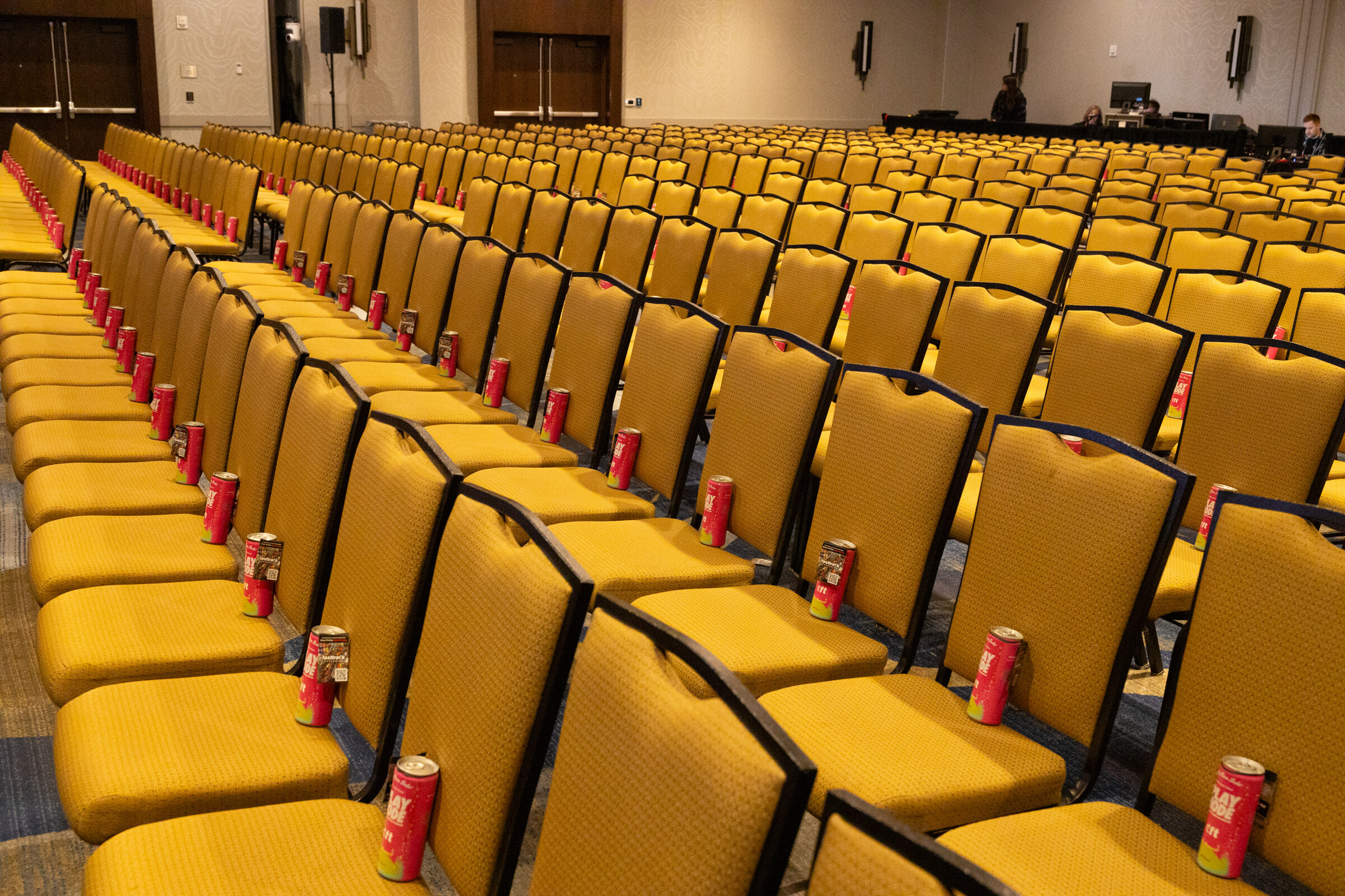 Rows of gold chairs each hold a small red can.