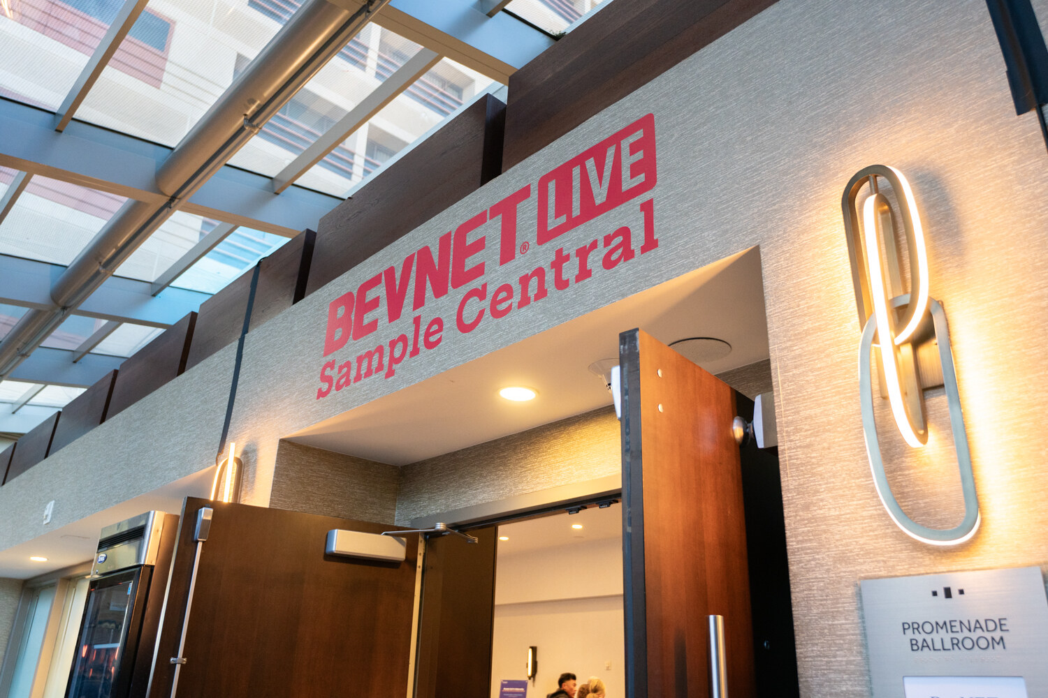 A BevNET Live Sample Central sign hangs over a skylit entrance.