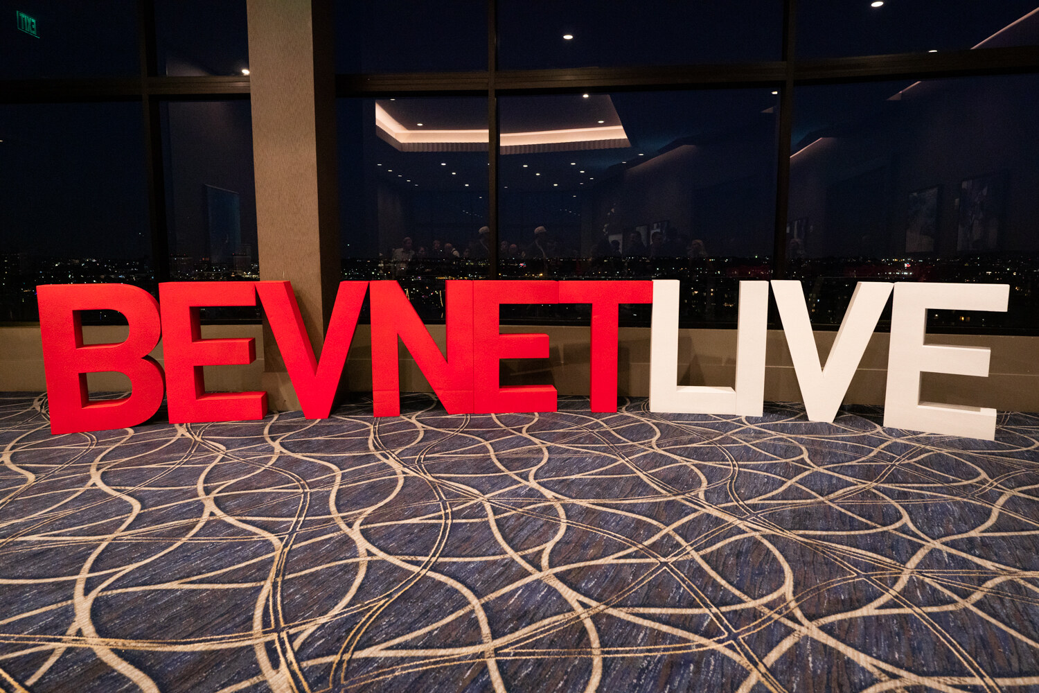 Large red and white BevNET Live letters stand on a patterned carpet.