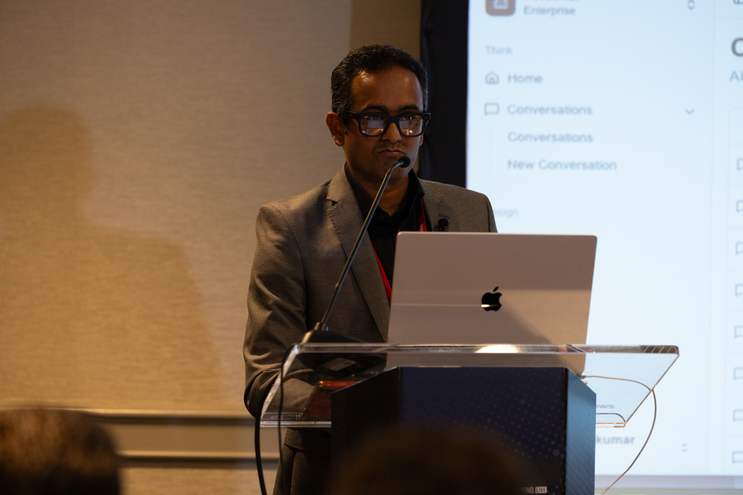 A man at a lectern presents with a laptop.