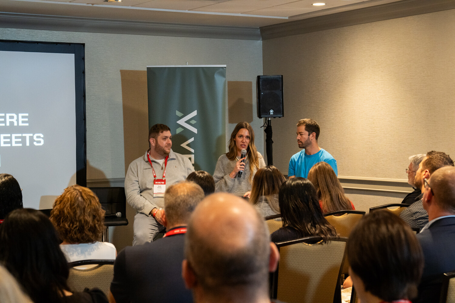 Attendees watch a panel in a meeting room.