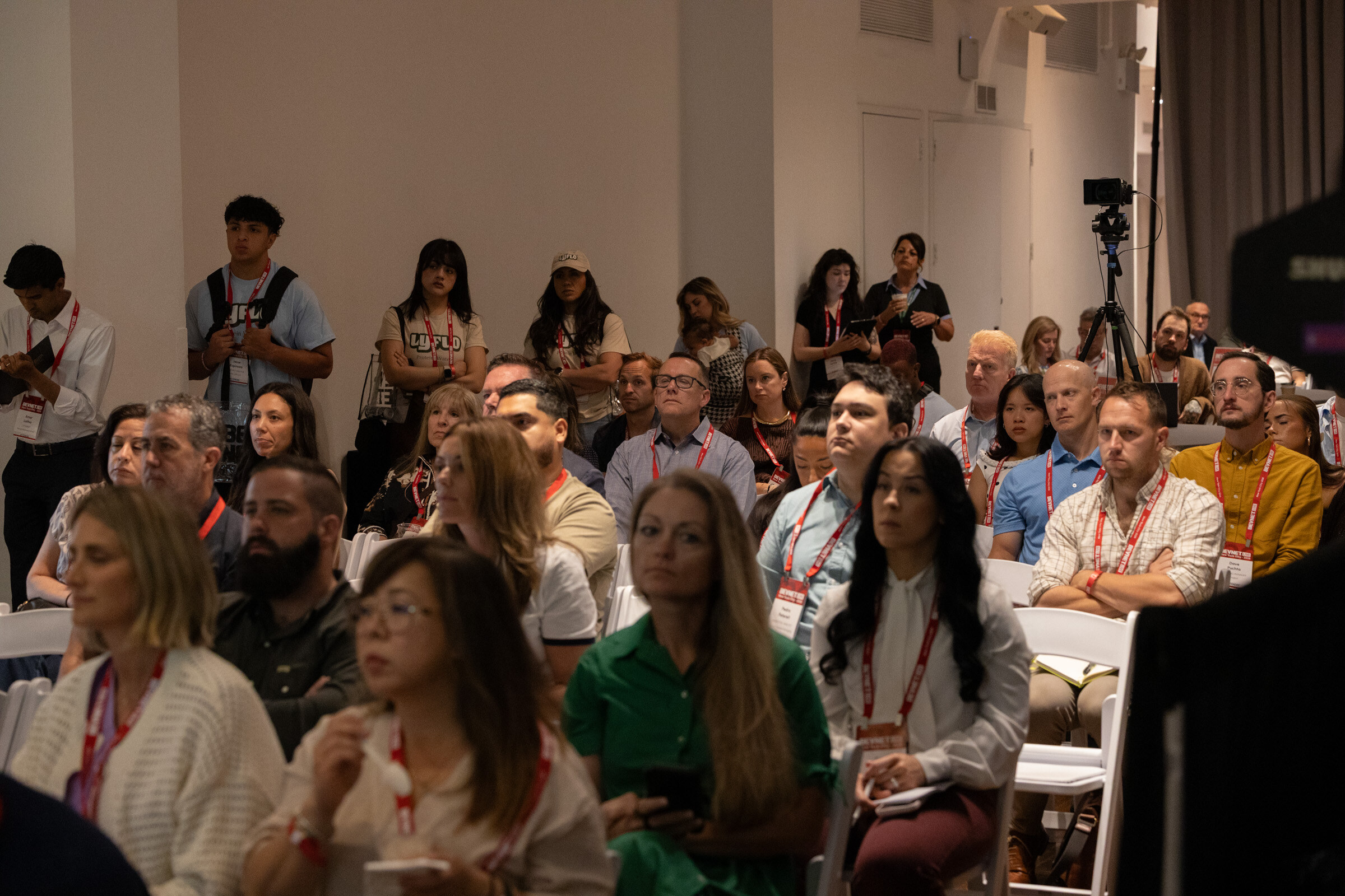 Rows of seated attendees with more people standing along the back wall.