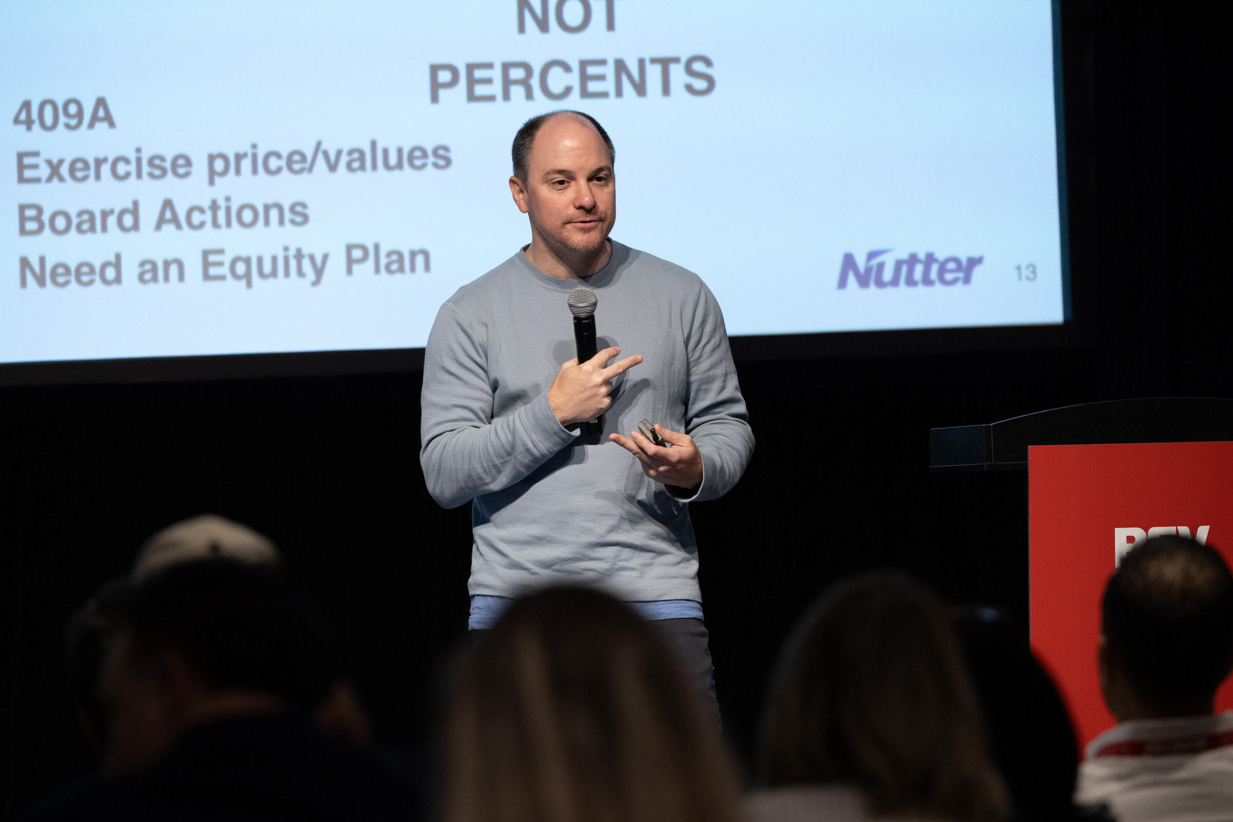 Speaker in a grey sweater before a Nutter slide listing 409A, exercise price, board actions and the need for an equity plan.