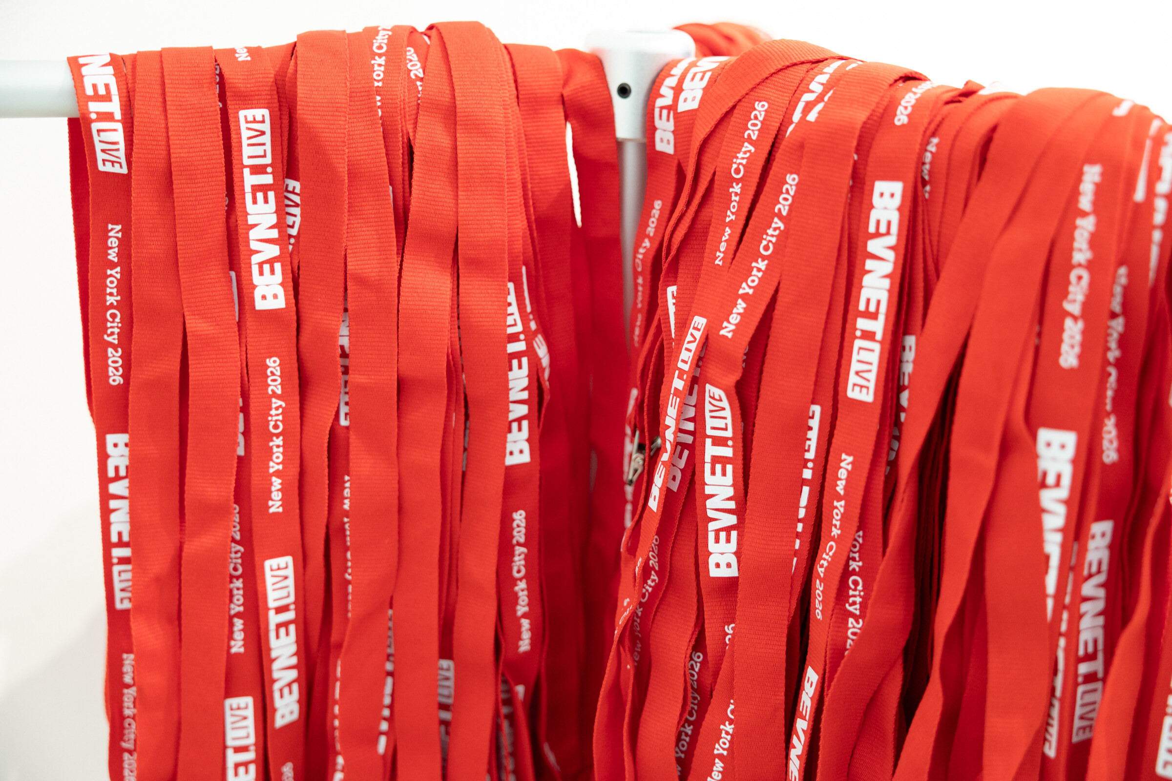 Close-up of dozens of red lanyards printed with BevNET Live and New York City 2026 hanging on a rack.