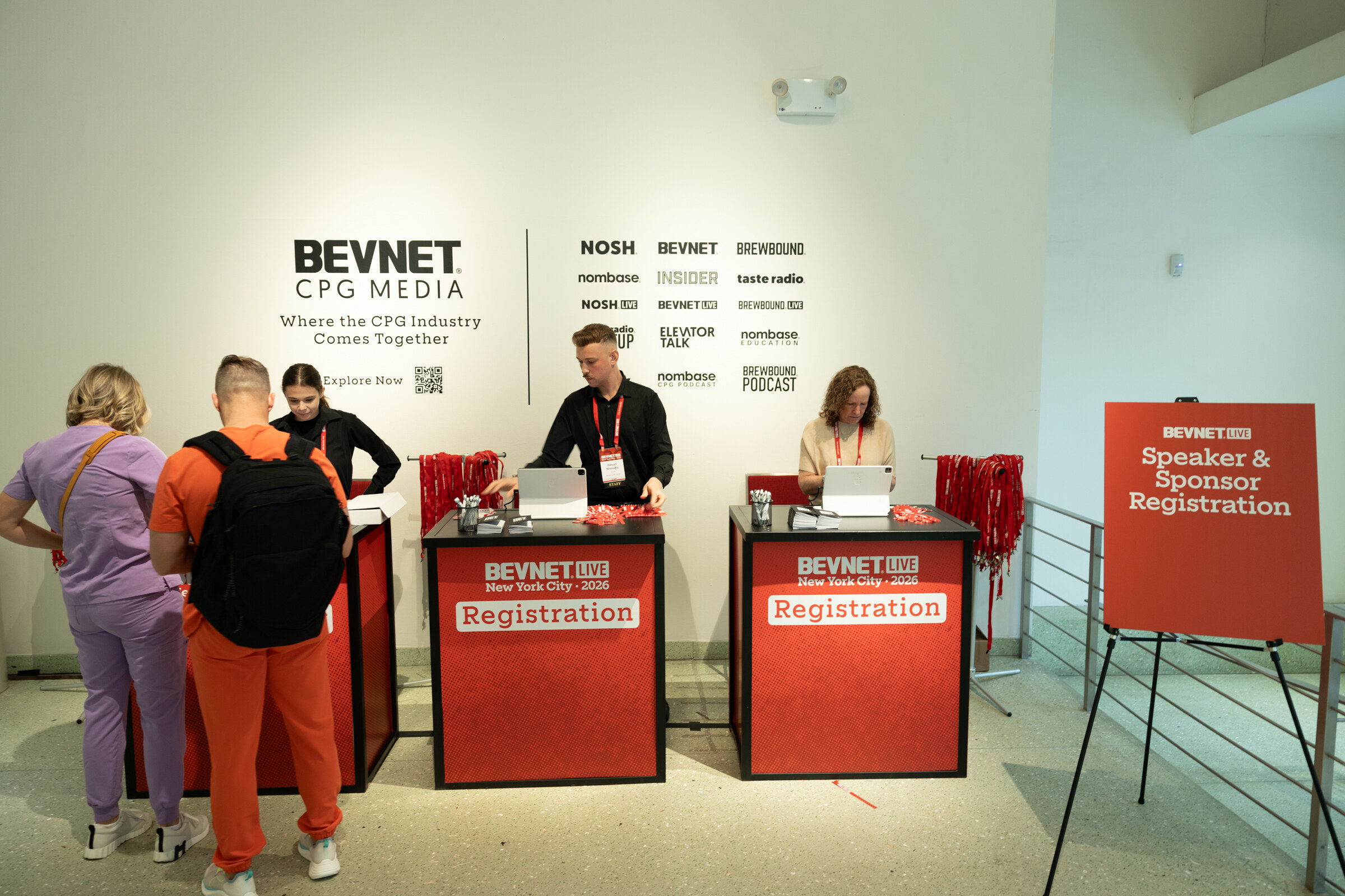 Attendees at two red BevNET Live registration desks in front of a white wall listing BevNET CPG Media brands, with a Speaker and Sponsor Registration sign at right.