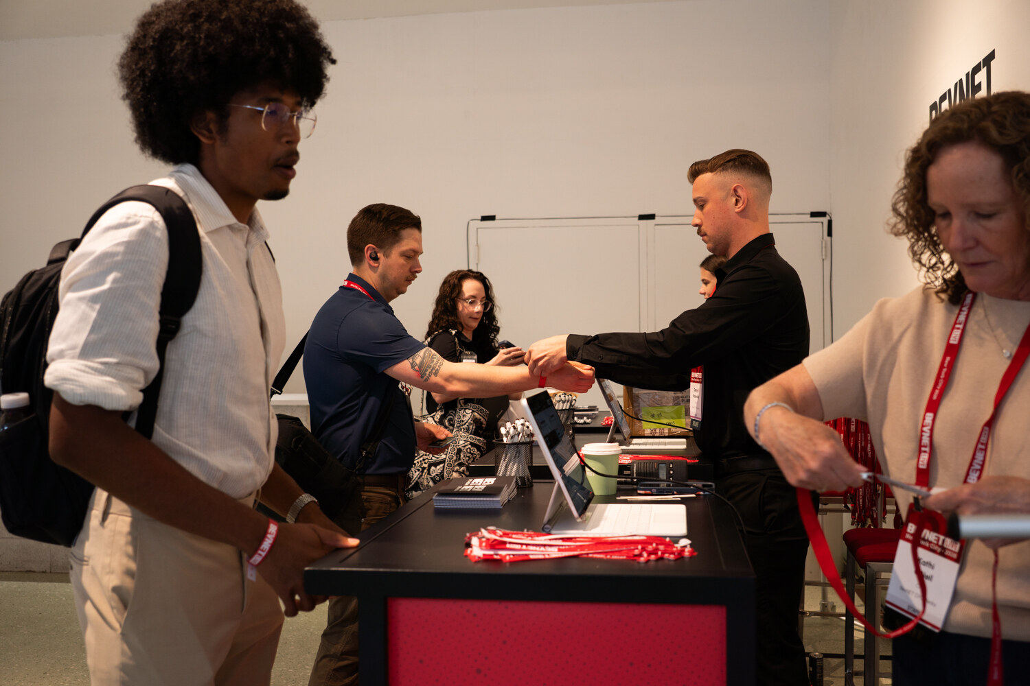 Attendees wait at a check-in counter while staff hand out red BevNET Live lanyards and fasten wristbands.