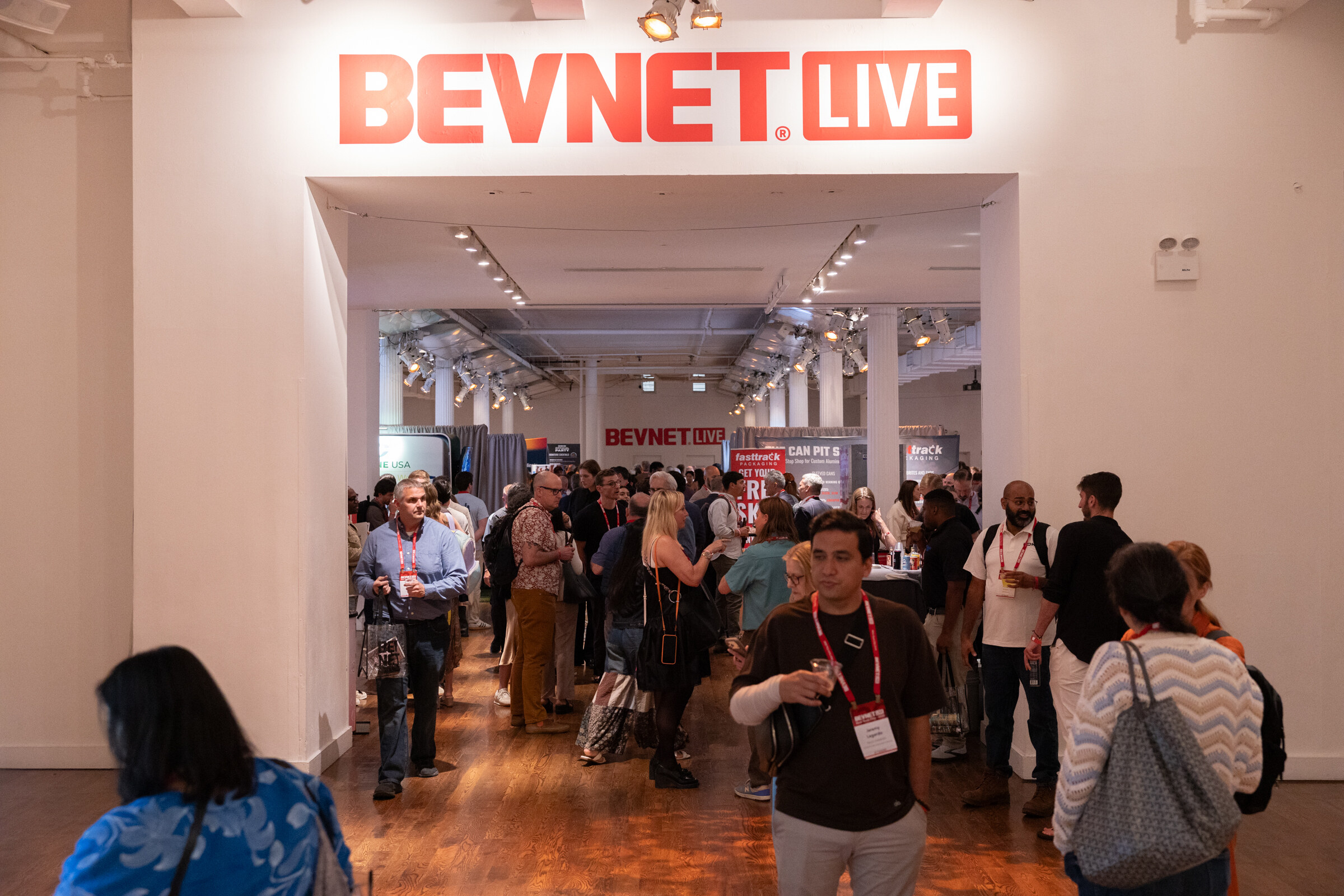 View through a white archway topped by a red BevNET Live sign into a busy hall of attendees.
