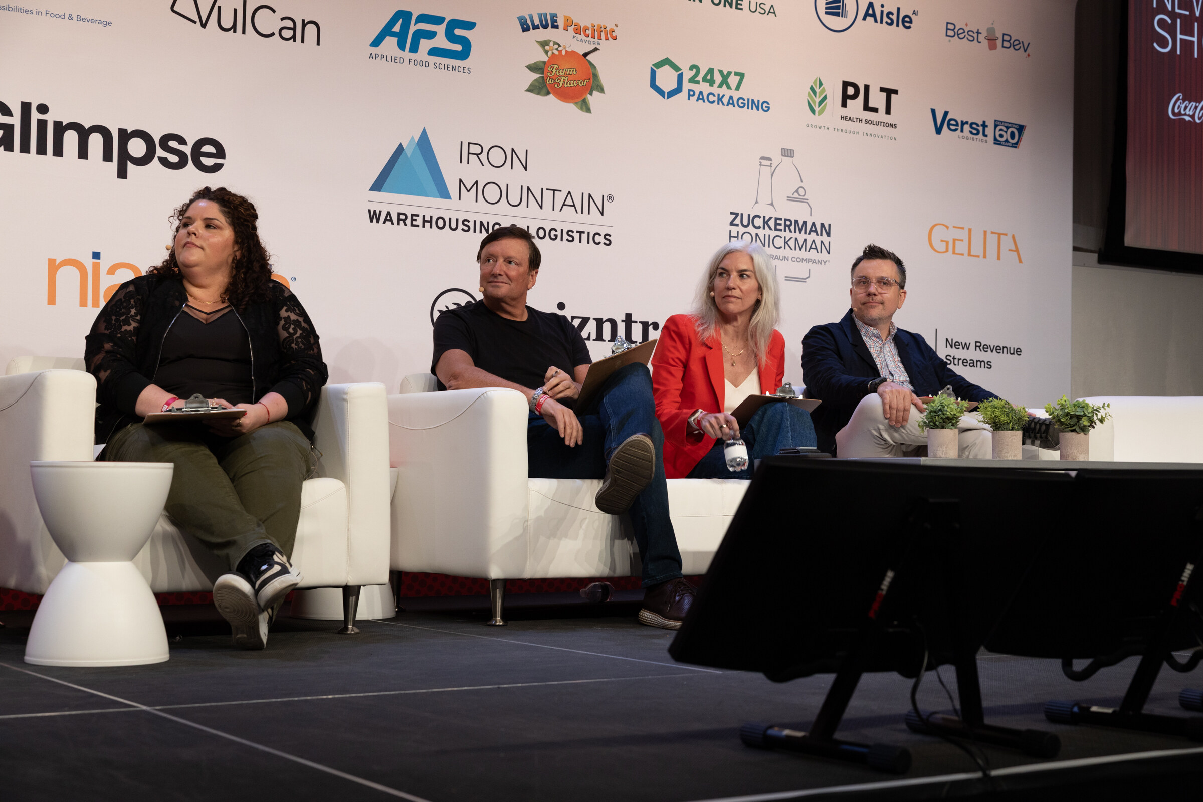 Four judges seated on white couches in front of a sponsor wall with Glimpse, Iron Mountain, Zuckerman Honickman and Gelita logos.