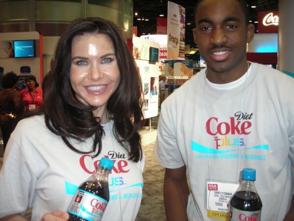 Larry O'Connor of Coca-Cola North America and a woman, both in Diet Coke Plus T-shirts, each hold a bottle of Diet Coke Plus.