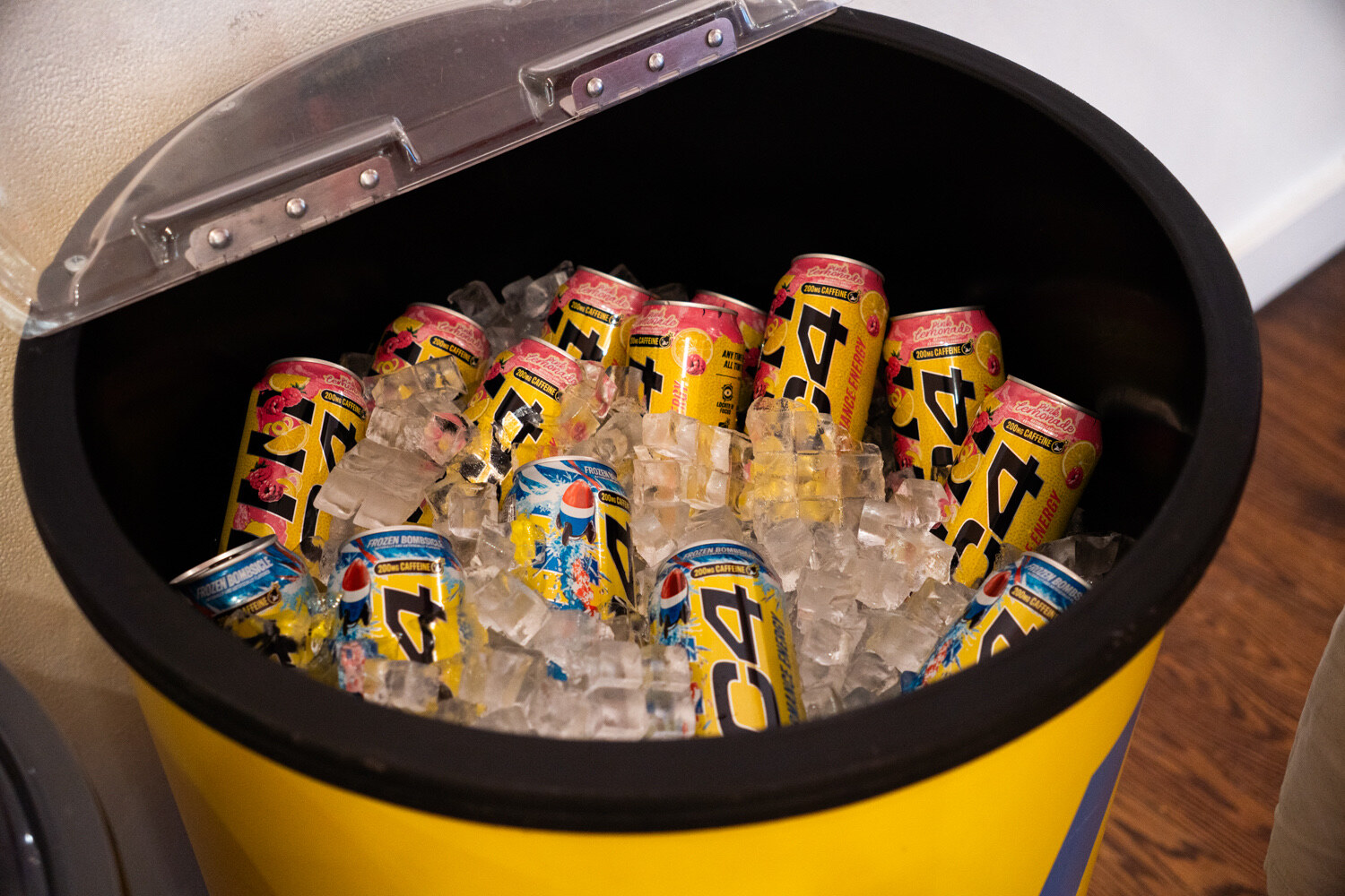 Yellow and black C4 Energy cans in ice inside a yellow cooler.