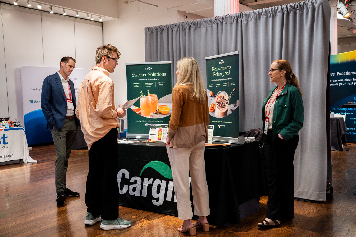 Four people talk in front of a black Cargill table and two green banners.