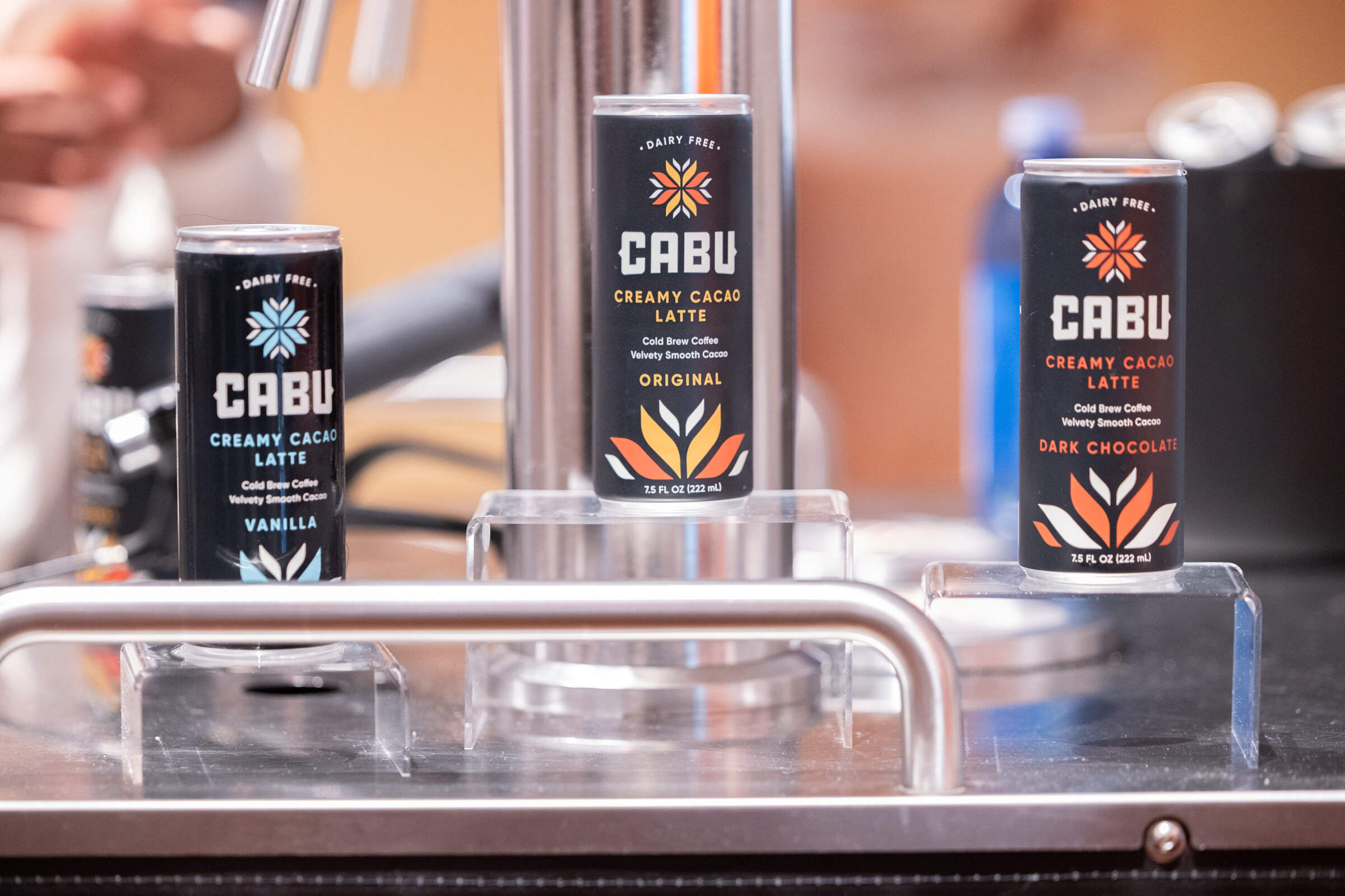 Three black CABU cans on clear risers on a steel cart.