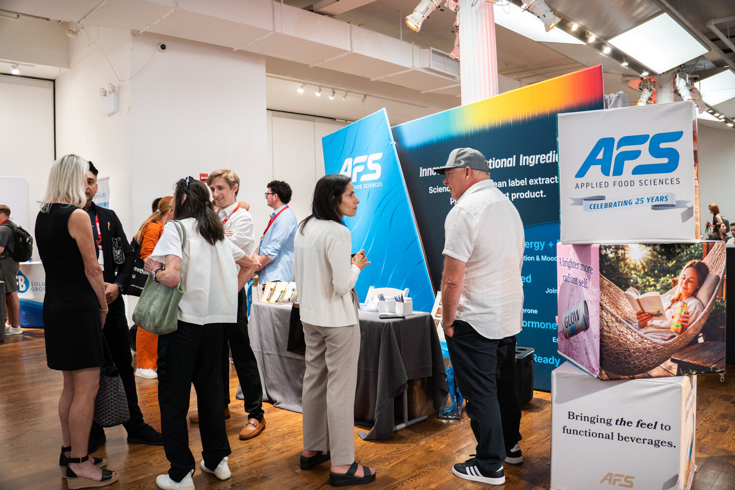 A group of attendees talks in front of blue AFS Applied Food Sciences banners.