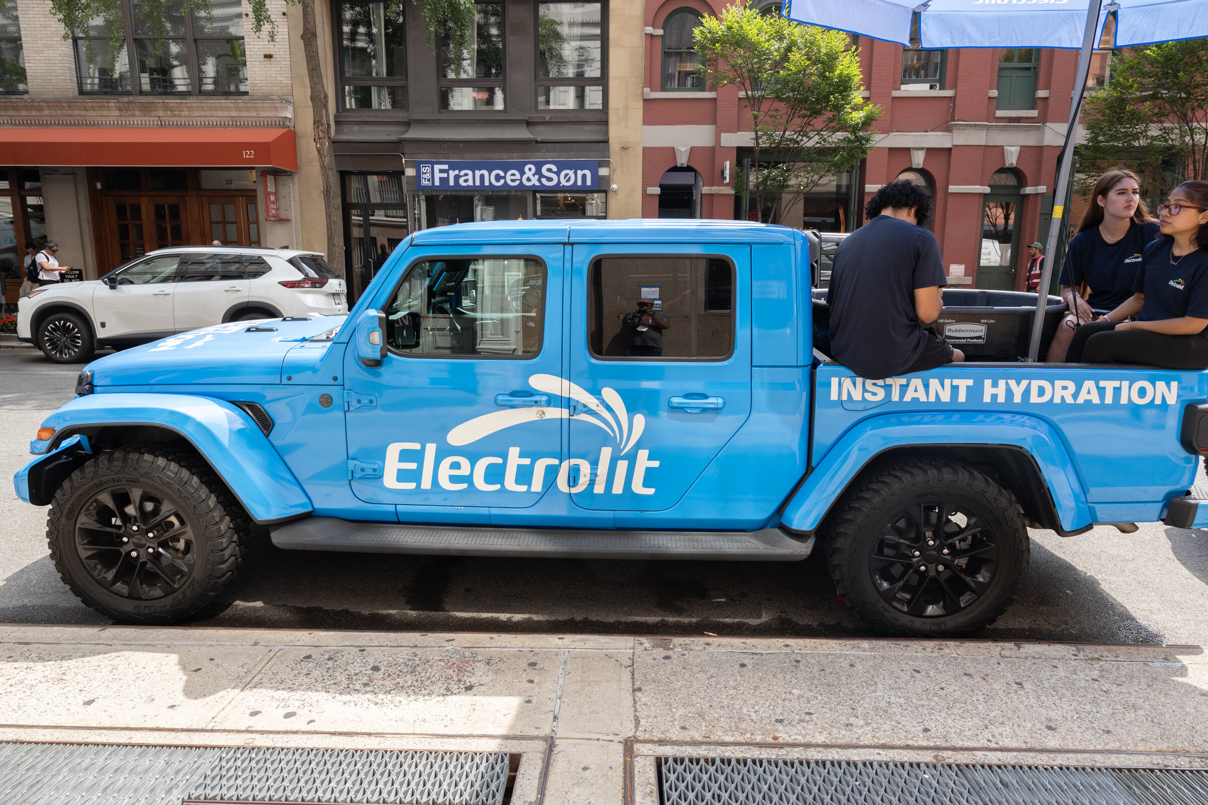 Side view of a blue pickup truck wrapped with the Electrolit logo and "Instant Hydration."