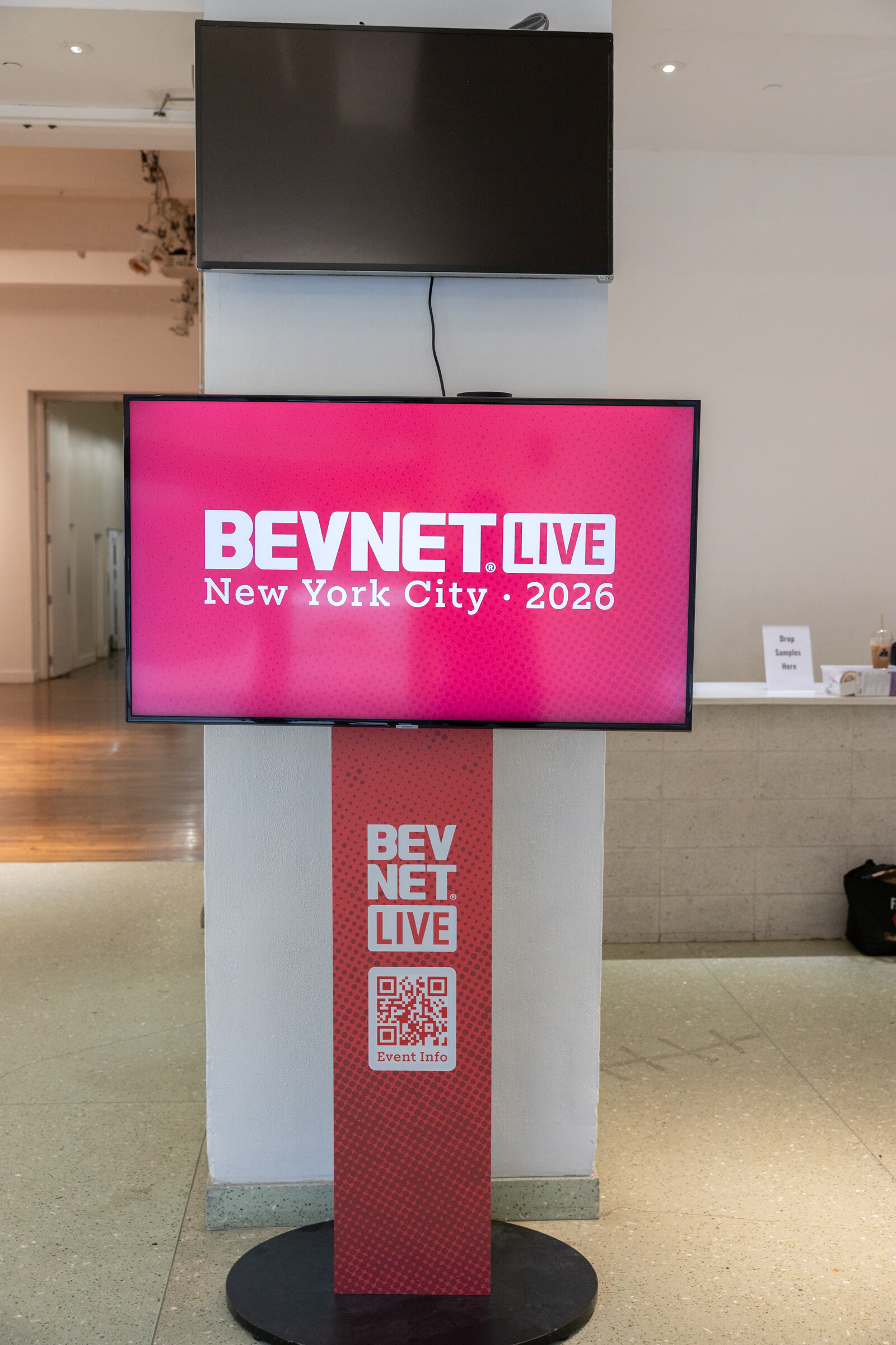 Pink digital screen reading BevNET Live New York City 2026 on a red BevNET Live kiosk stand.