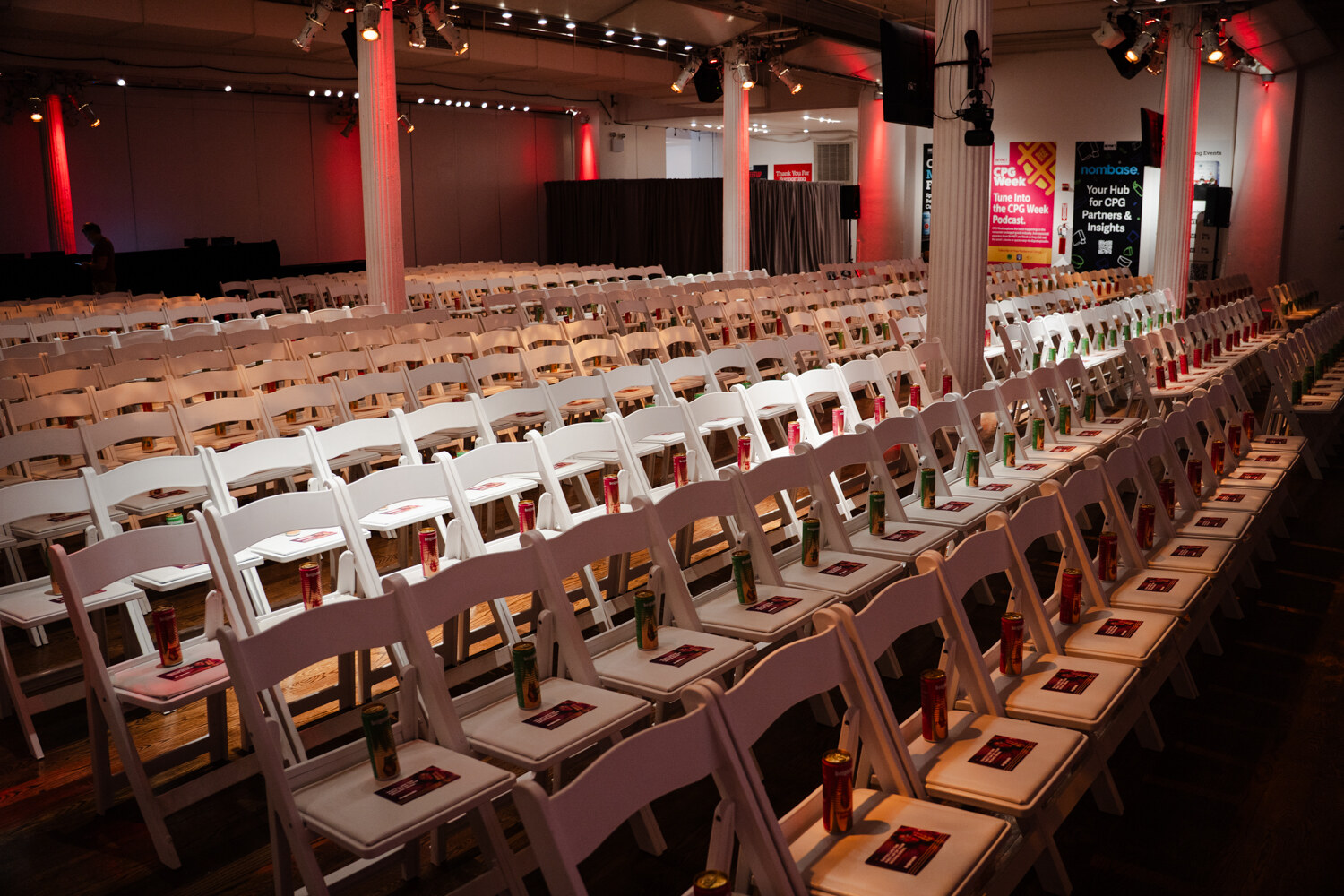 Long rows of white folding chairs, each holding a Brightside can and a card, in the main session hall.