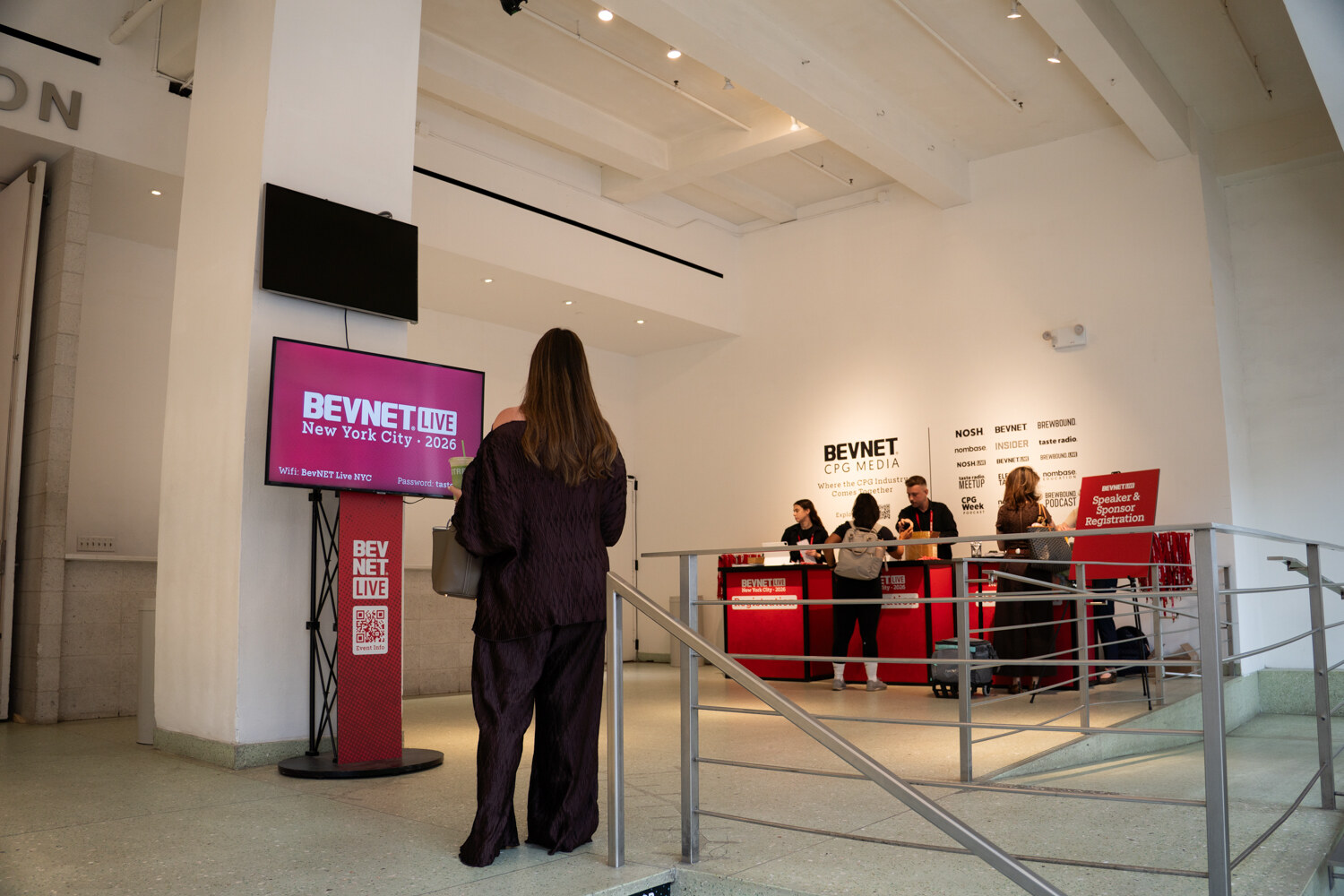Attendee walking past a digital screen reading BevNET Live New York City 2026 toward red registration desks.