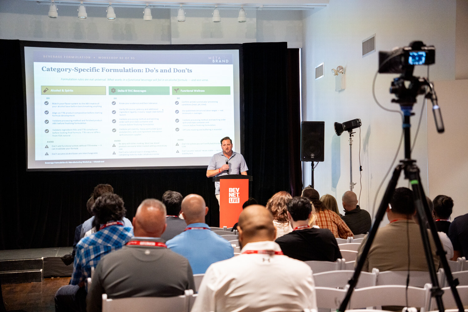 Speaker at a red BevNET Live podium beside a slide titled “Category-Specific Formulation: Do’s and Don’ts,” with attendees and a camera in the foreground.