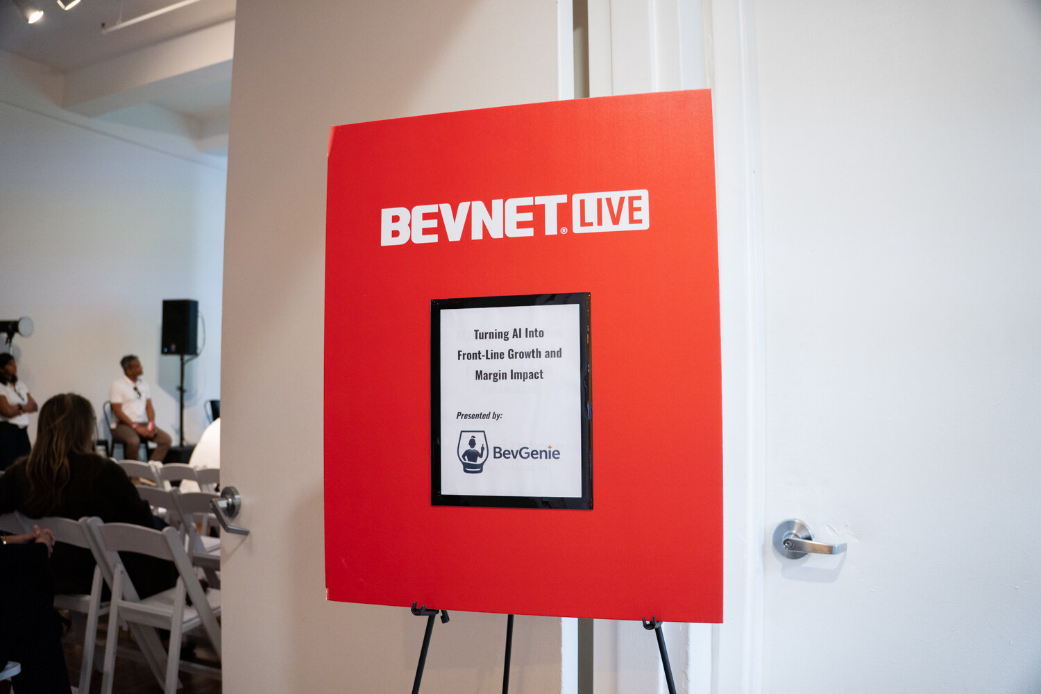 Red BevNET Live easel sign with the BevGenie workshop title beside the open door of the session room.