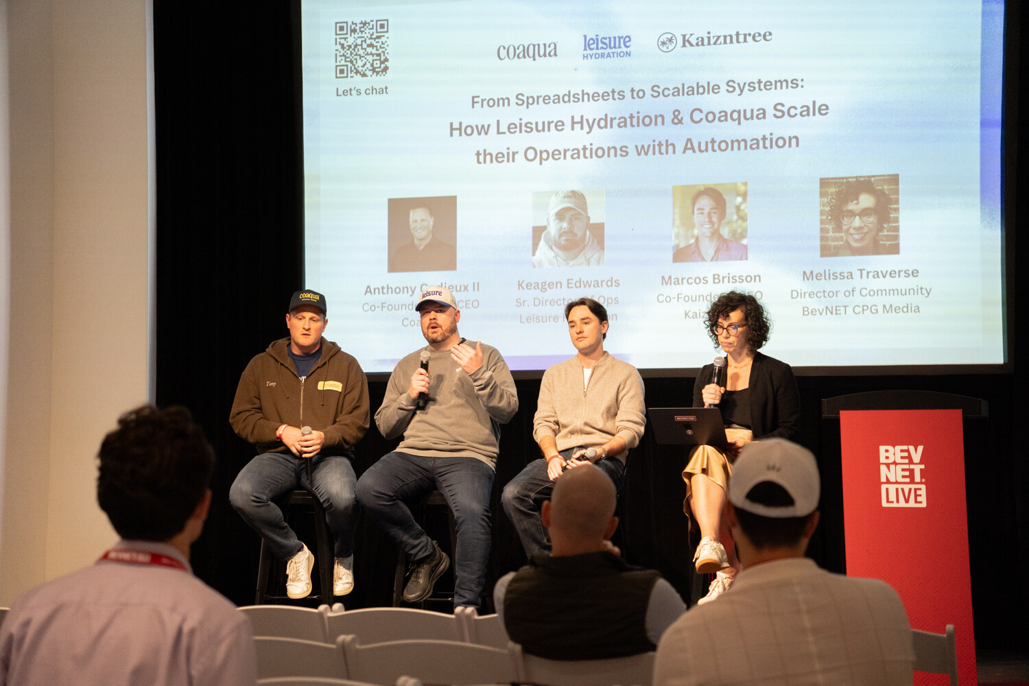 Four panelists on stools beside a red BevNET Live podium, a slide with their photos and titles behind them.