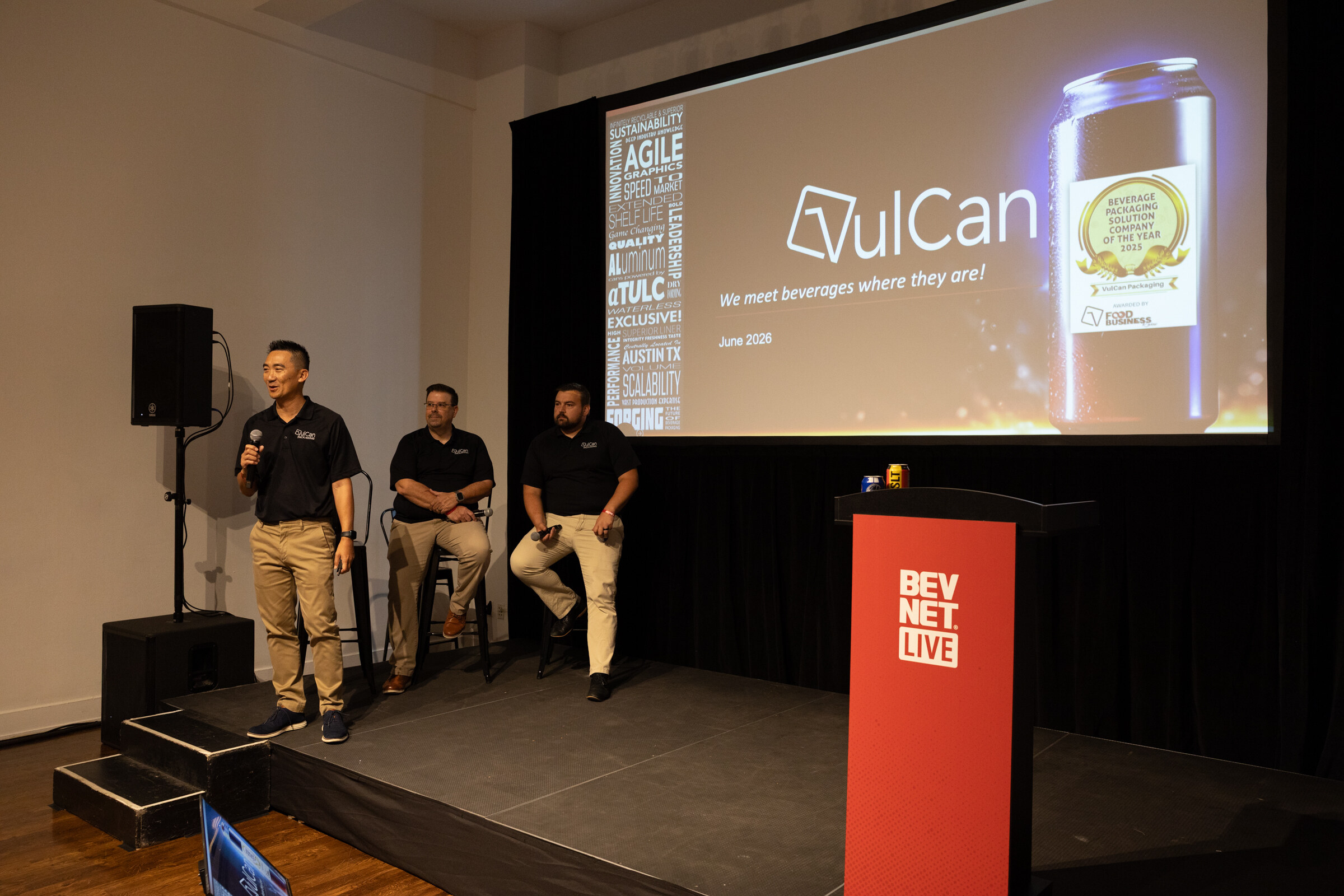Three men in black VulCan polos on stage, one speaking, beside a VulCan title slide and a red BevNET Live podium.